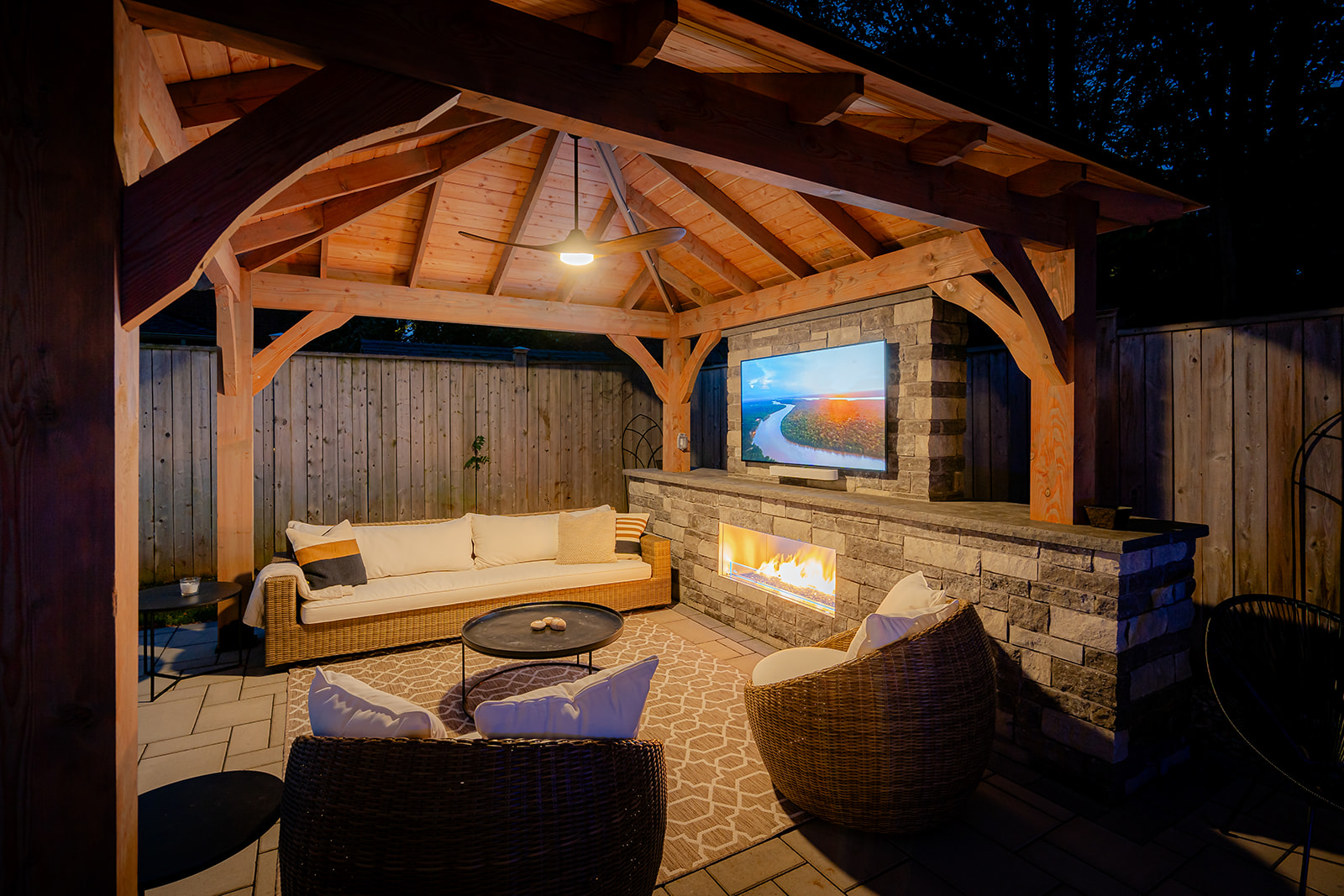 An outdoor patio set with the tv on underneath the gazebo.