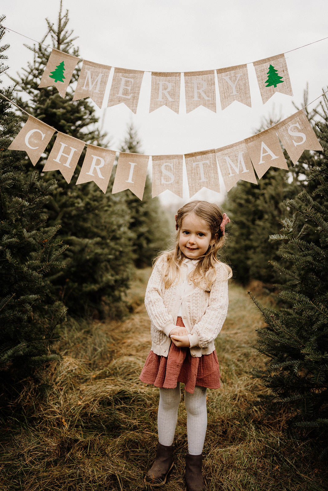 A little girl underneath a 'Merry Christmas' banner.