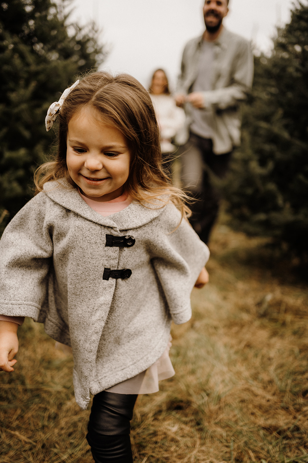 A little girl running between Christmas Trees.