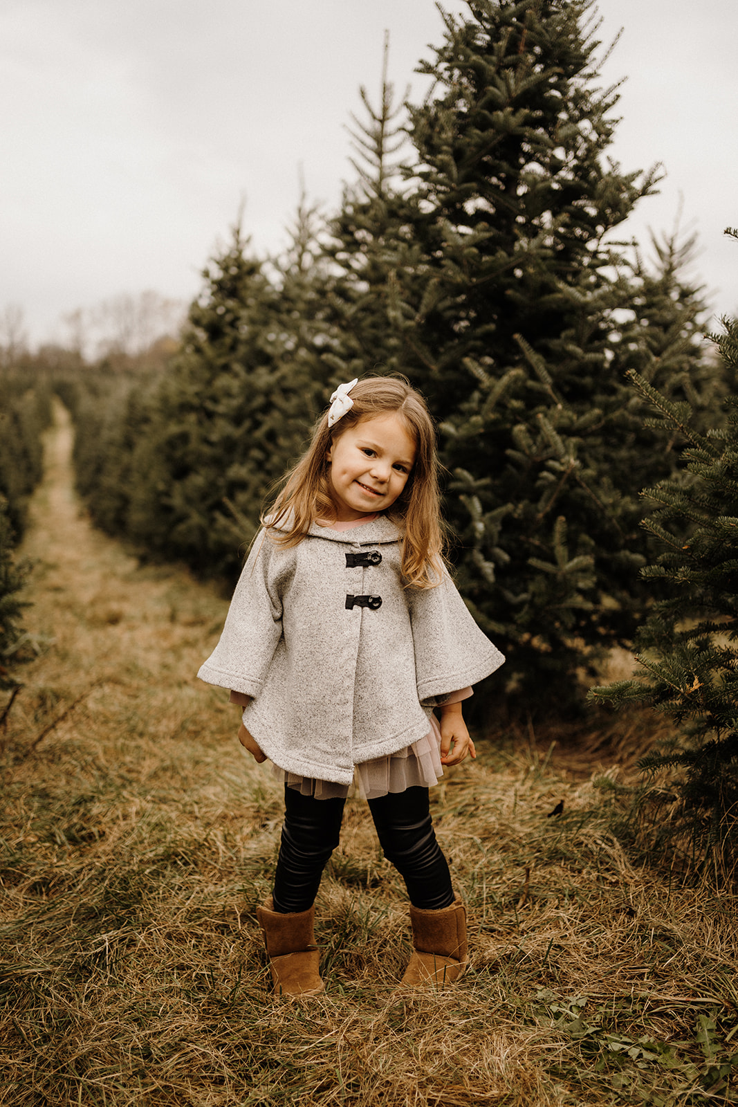A little girl standing in front of Christmas Trees.