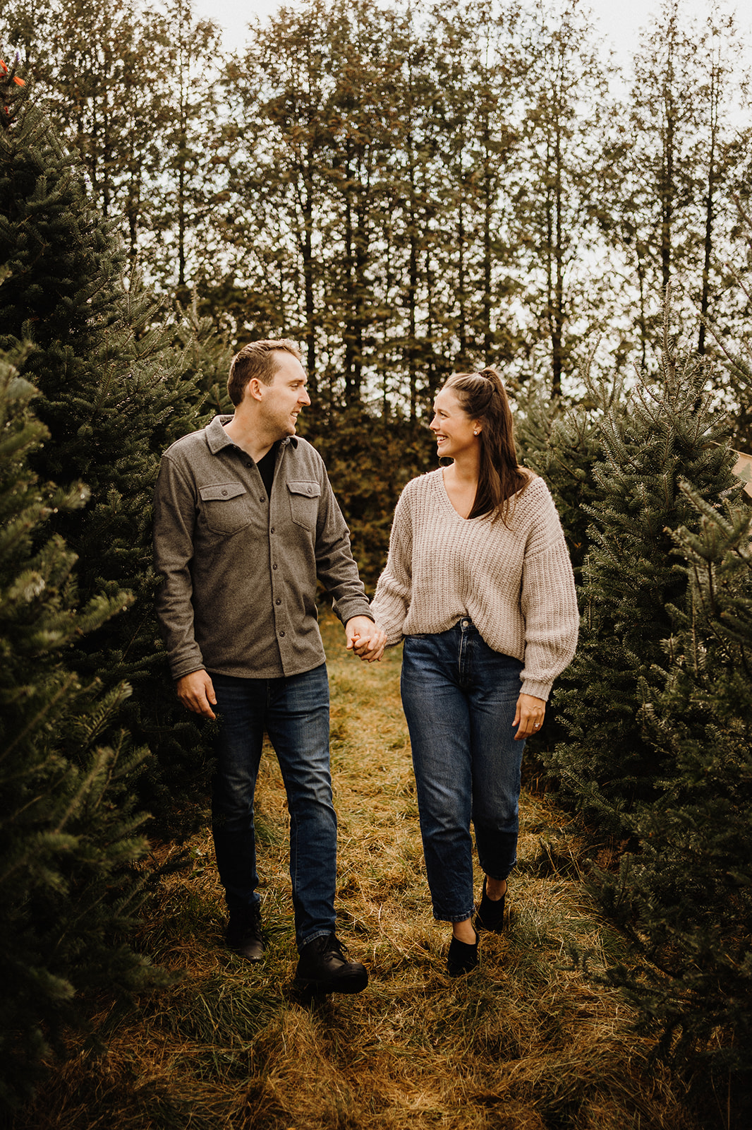 A husband and wife walking between Christmas Trees.