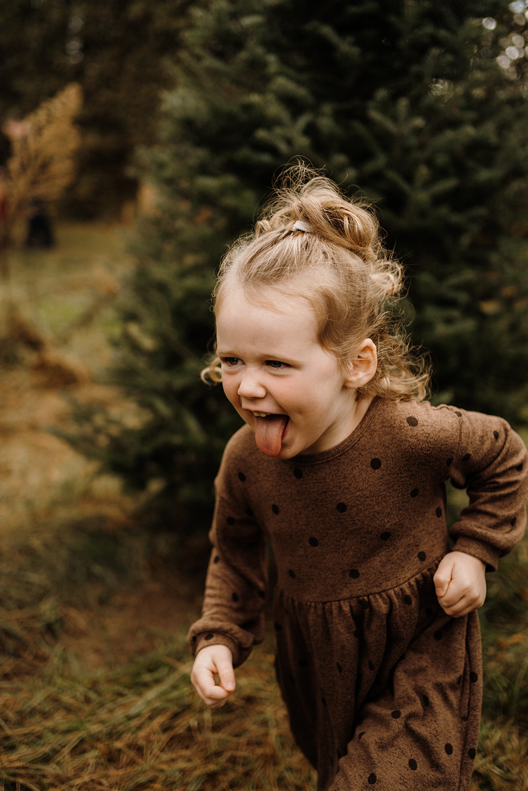A little girl running outside with her tongue out.