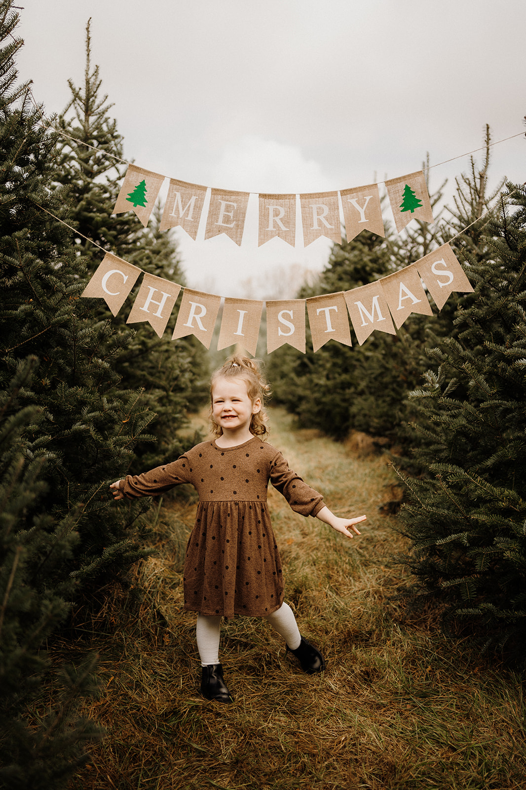 A little girl underneath a 'Merry Christmas' Banner