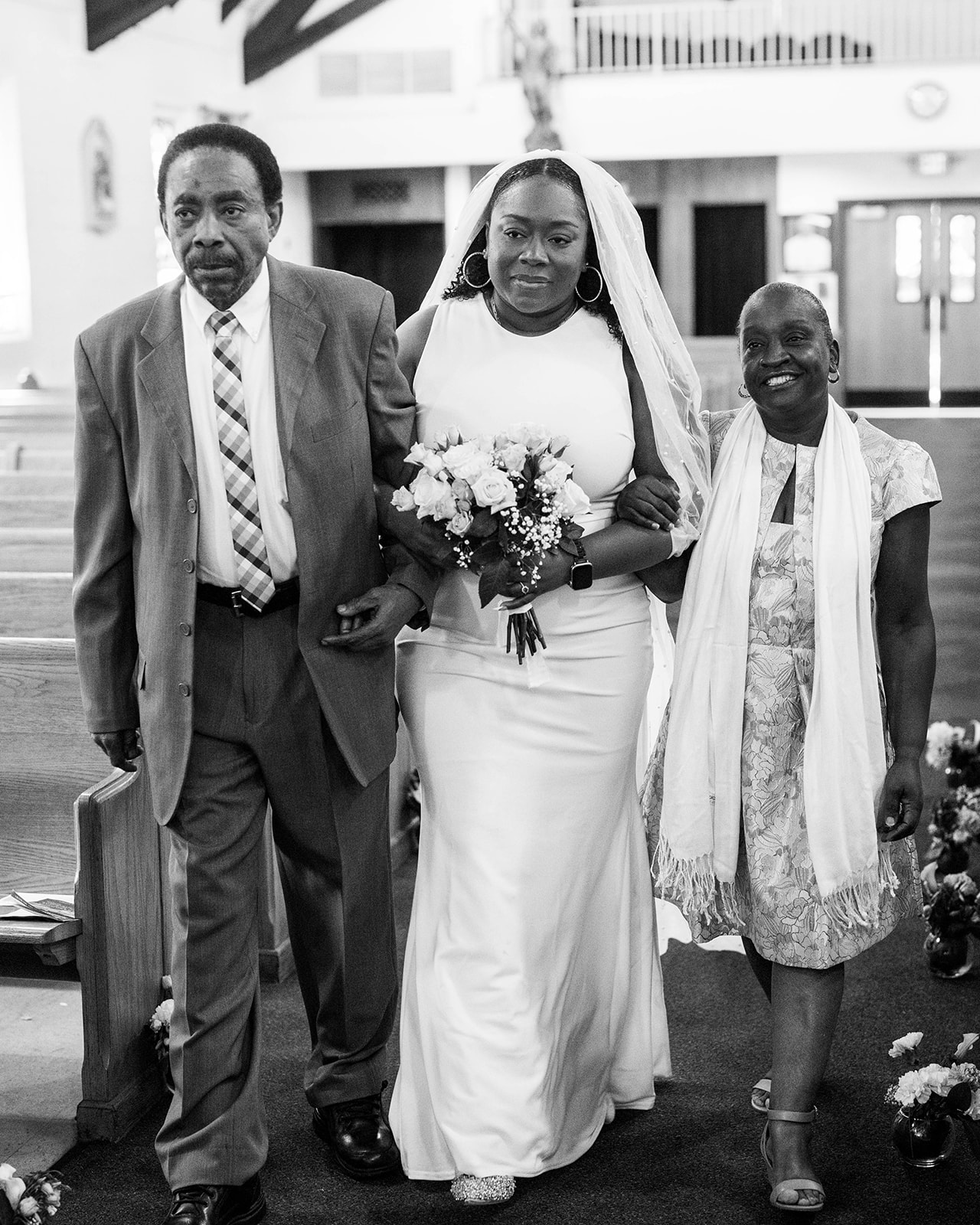 bride and parents walking down the aisle in black and white