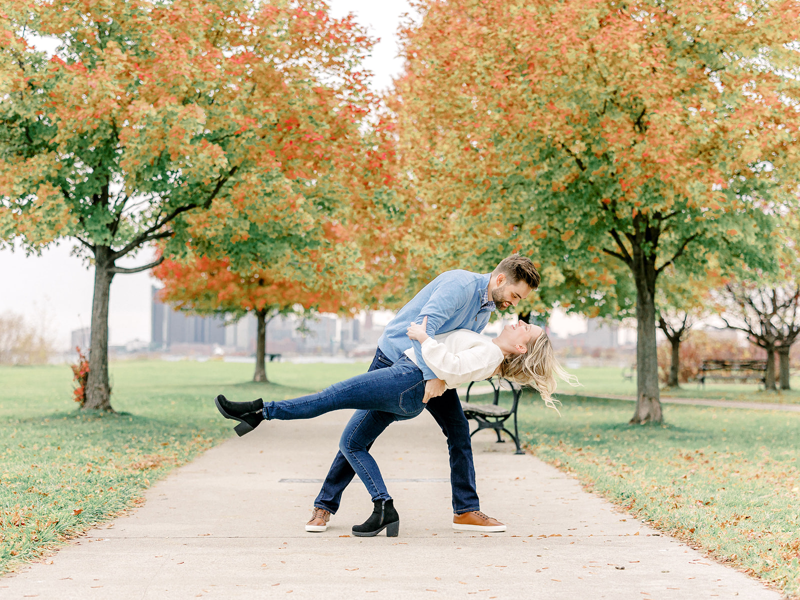 Couple kiss with fall leaves behind them at their Belle Isle Detroit engagement session.