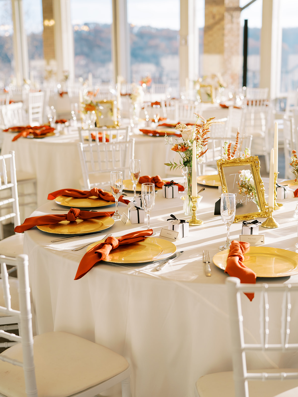 A bright white, red, and gold table setting at a wedding reception at Hunt Valley Country Club.