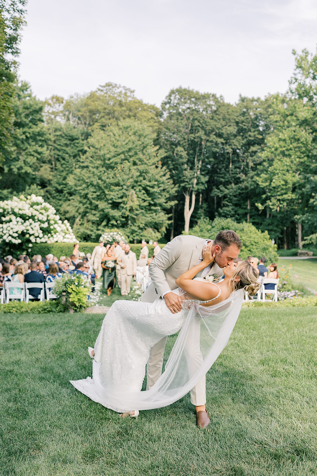 summer ceremony in sunken garden at smith farm gardens married couple kissing at the end of the aisle