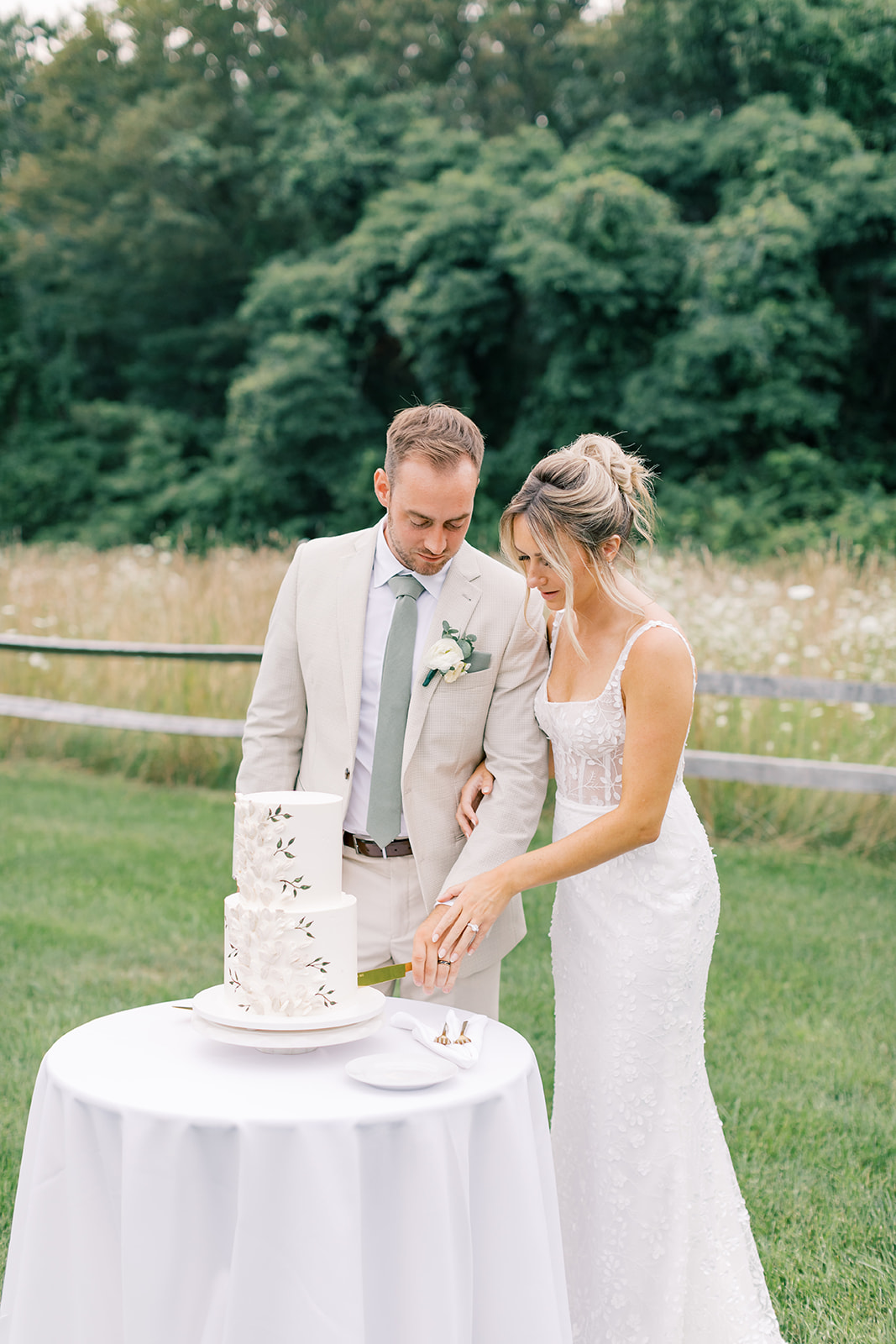 bride and groom cutting custom floral cake with field in the background