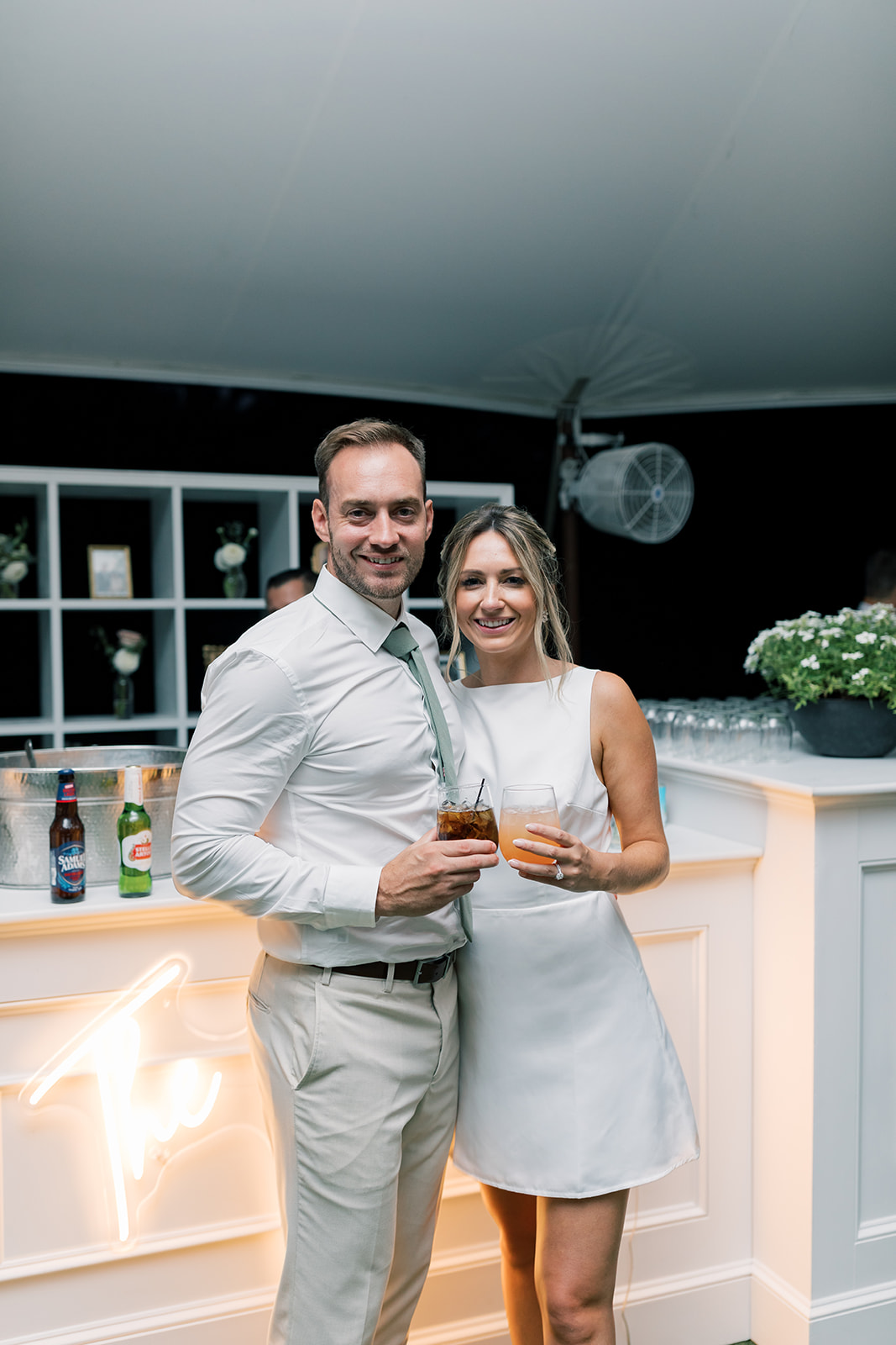 couple posed with signature cocktails in front of bar at smith farm gardens reception