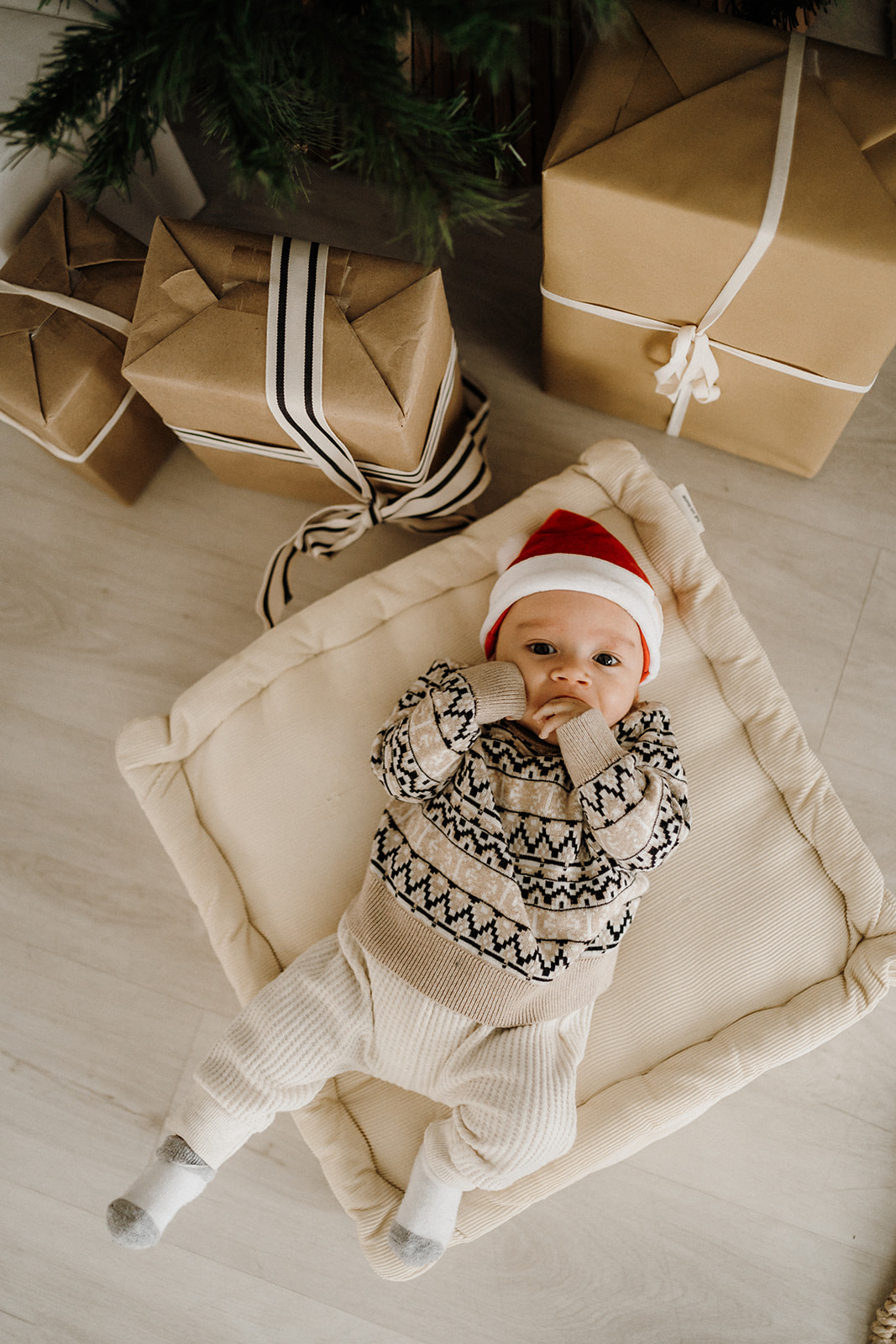 Baby lying down on a blanket beside presents.