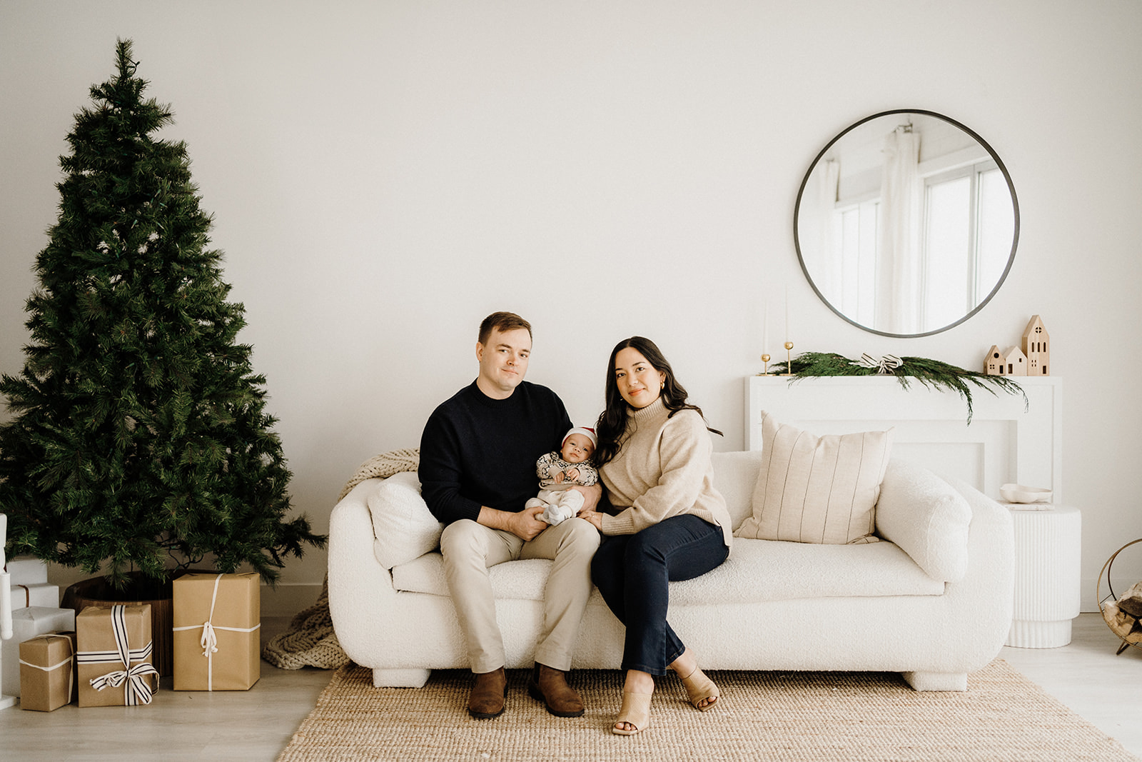 A family of three sitting on the couch with a tree on the left.