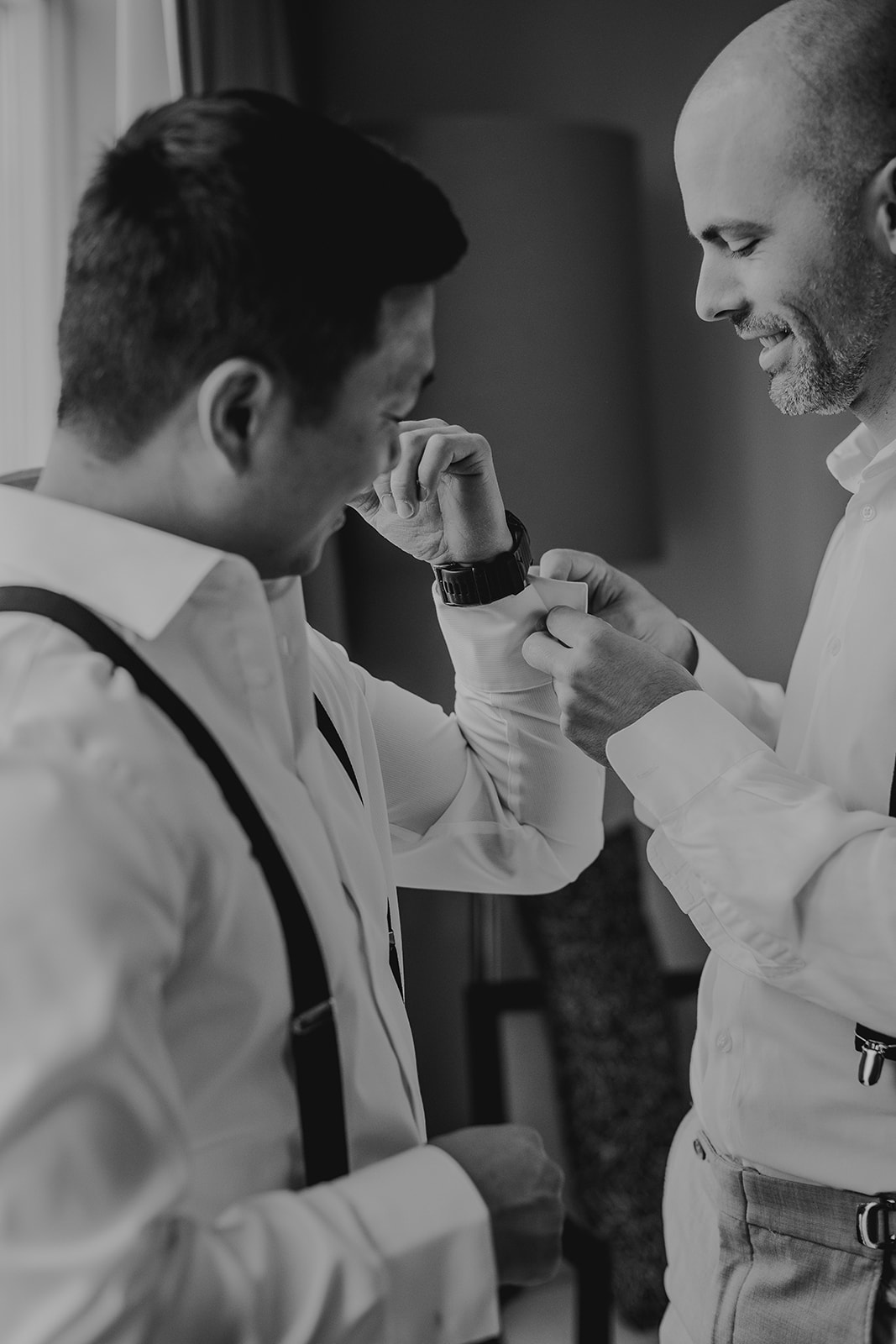 a best man helps a groom with his shirt 