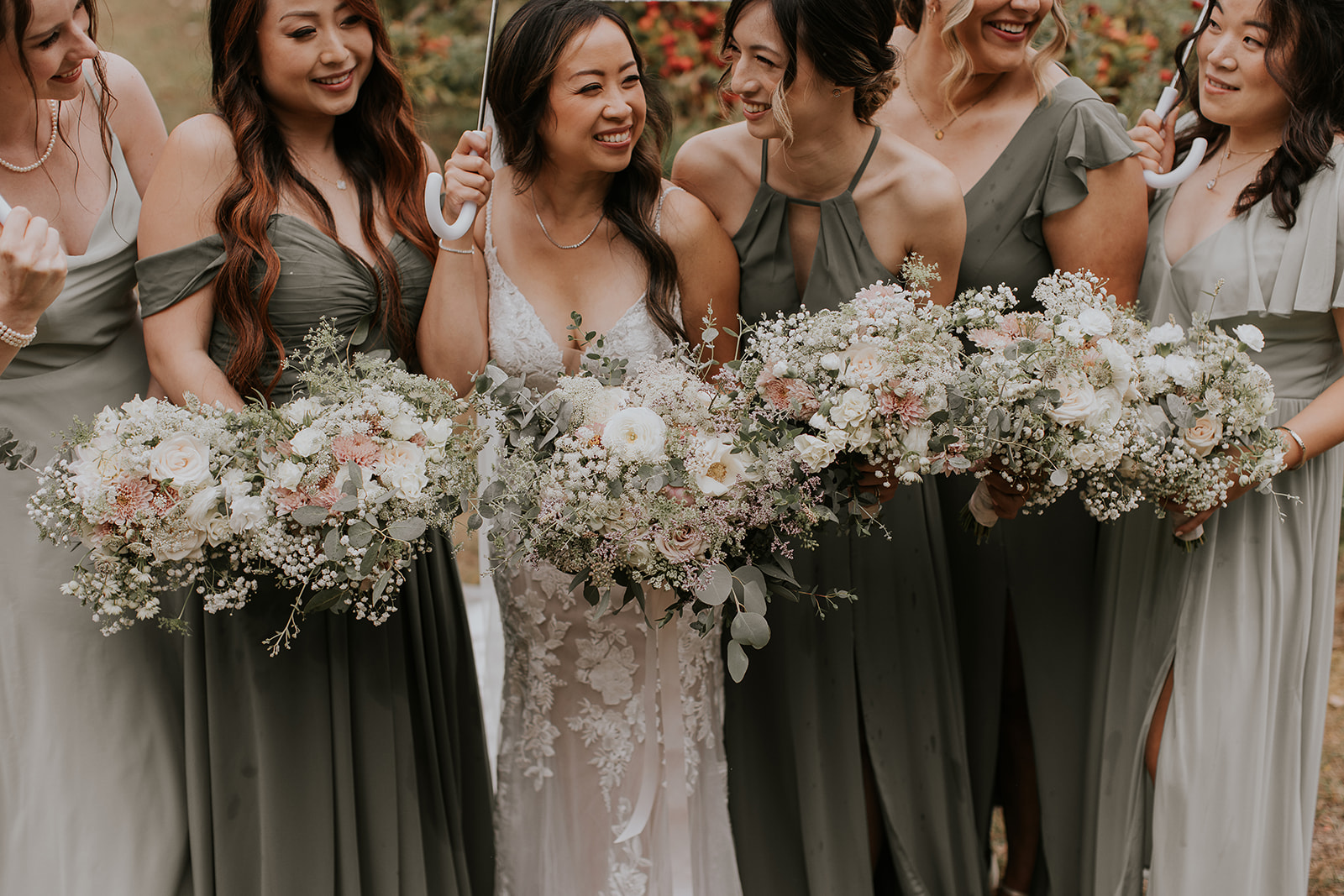 bridesmaids hold their flowers and laugh at each other 