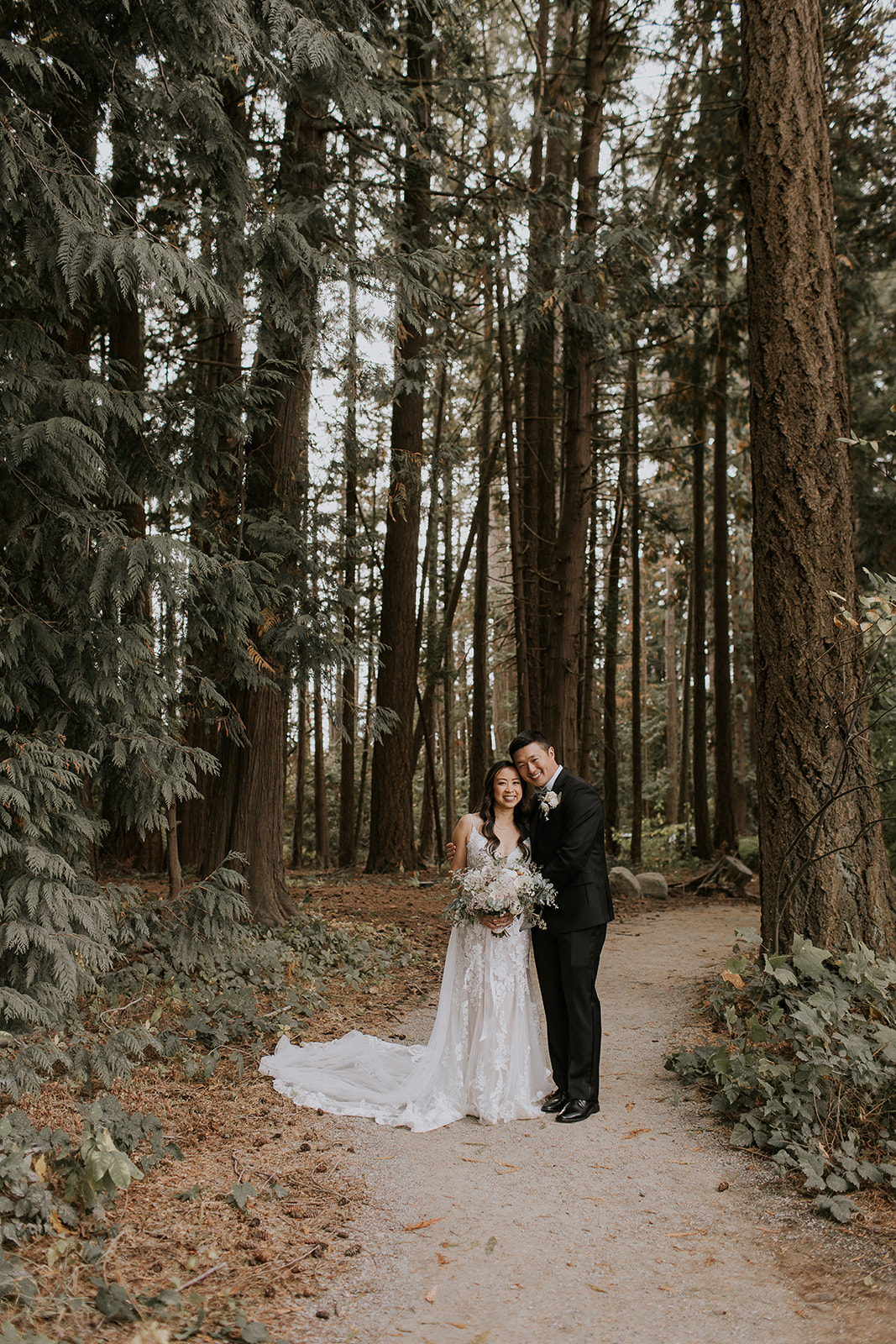 a groom and bride stand in a forest at Sea Cider Farm 