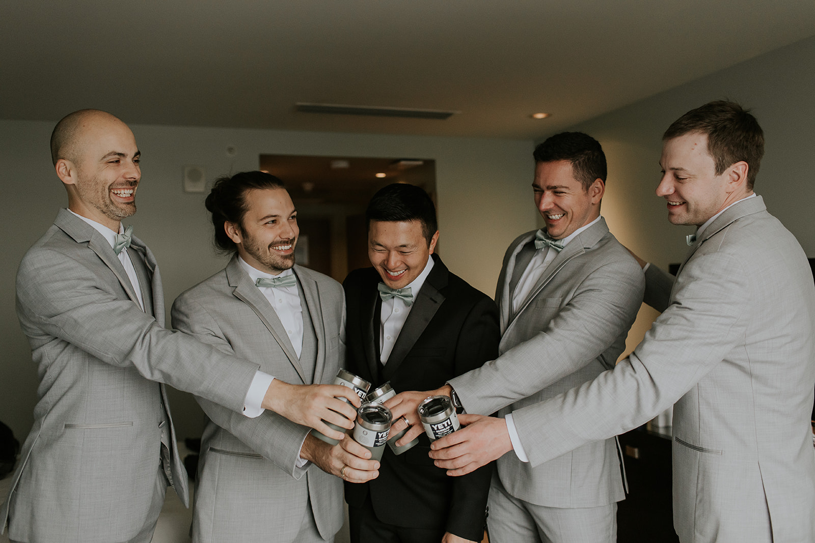 a groom and his groomsmen cheers with their yetis