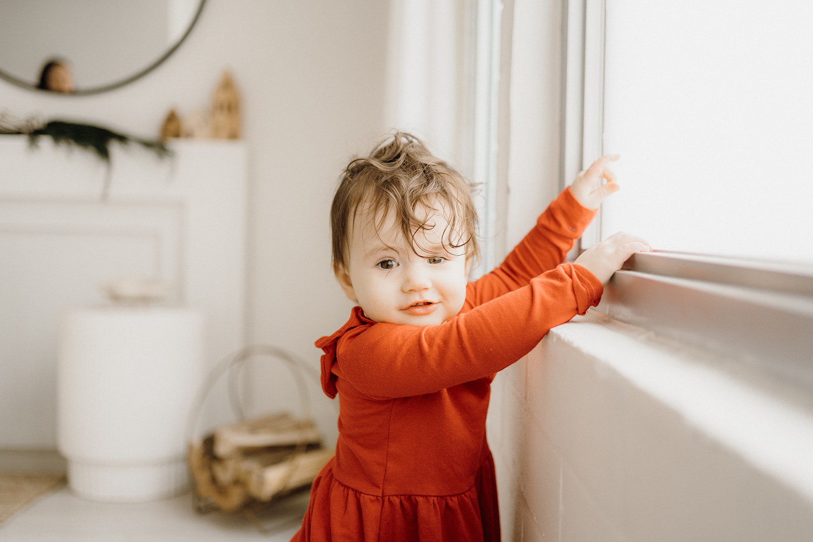 A toddler standing, touching the window.