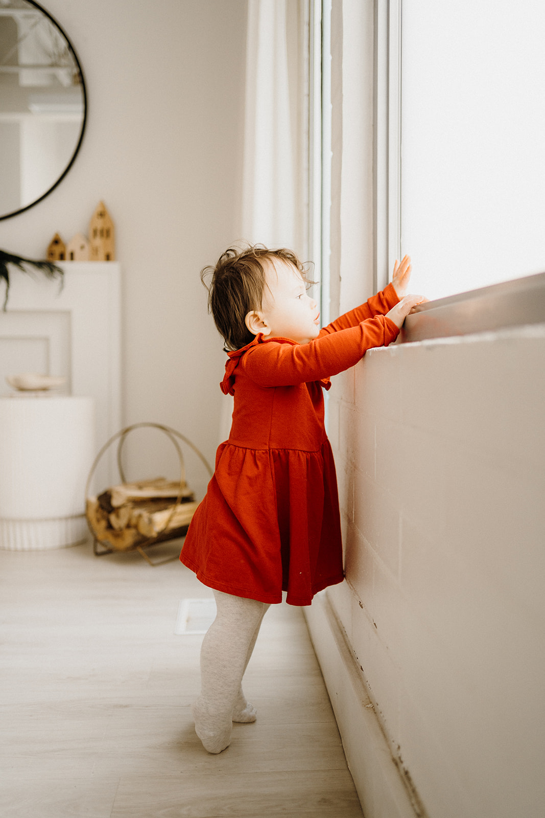 A toddler standing, touching the window.