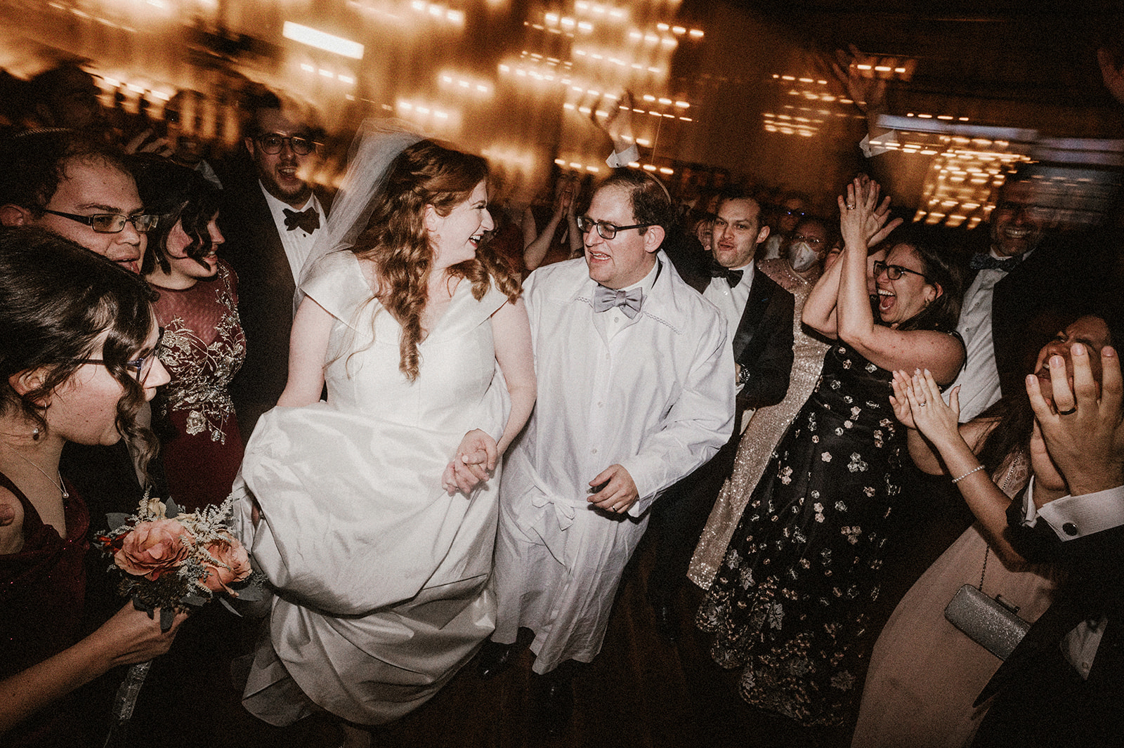 bride and groom joyfully escorted out of chuppah ceremony surrounded by family and friends