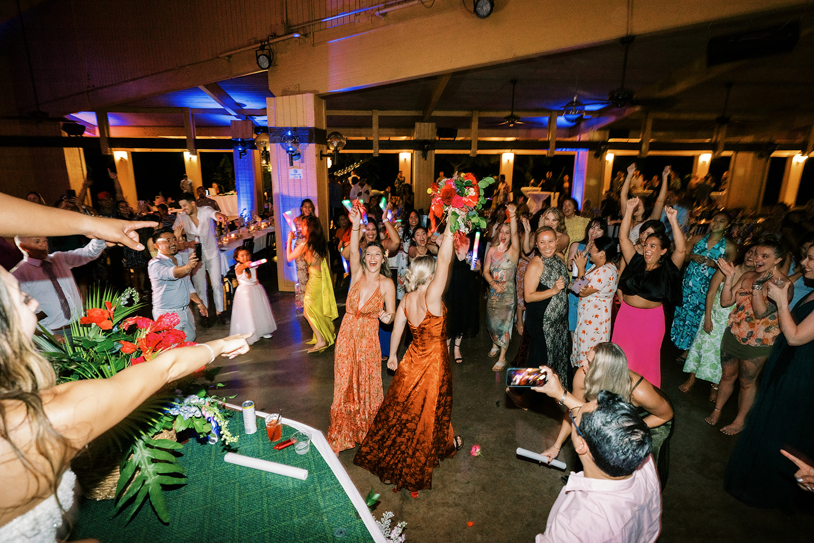 A lively bouquet toss at a wedding reception with guests excitedly reaching out in Smiths Tropical Paradise Luau