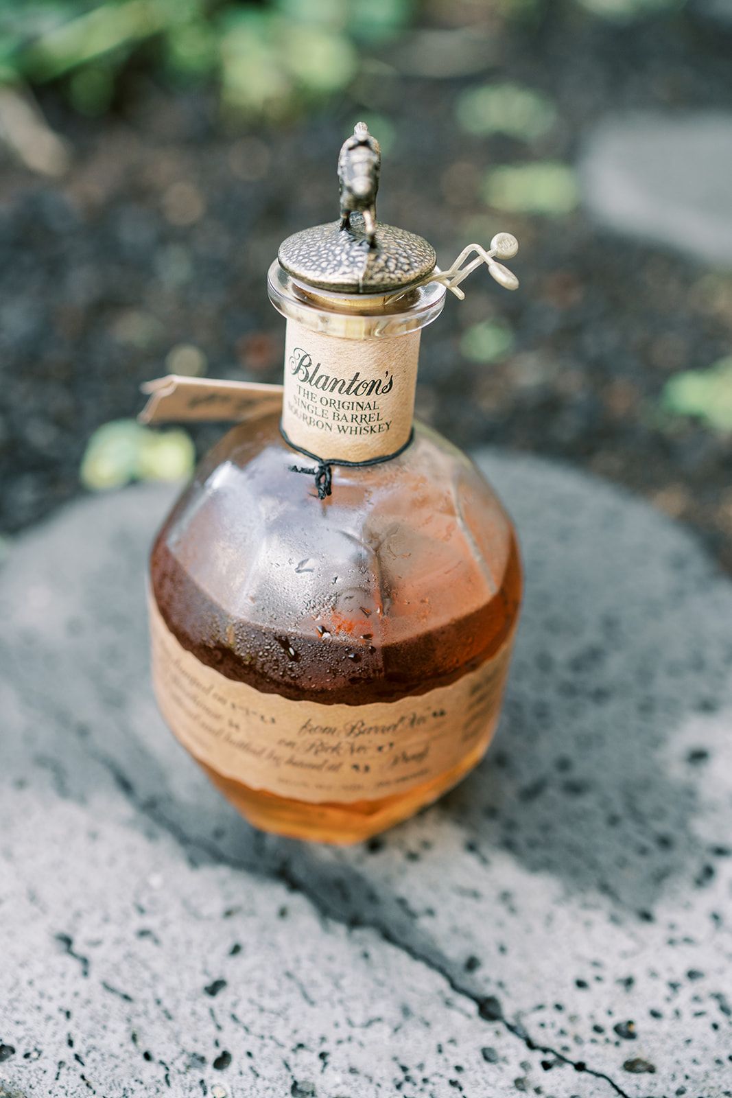 A bottle of blanton's single barrel bourbon displayed on a textured surface with condensation at Hawaiian Wedding.