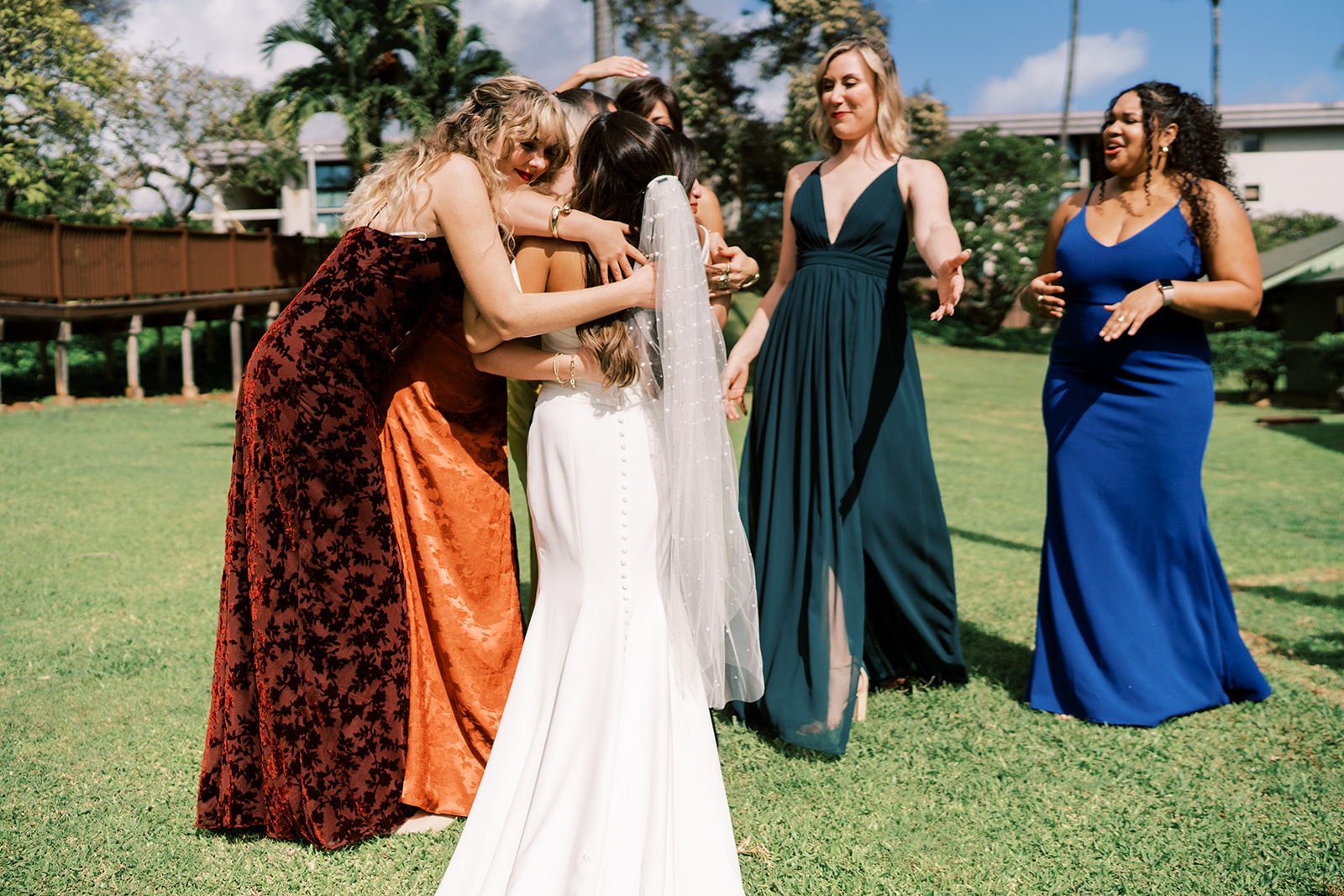 Two women embracing a bride while two other guests look on, at an outdoor Hawaiian wedding in Kauai