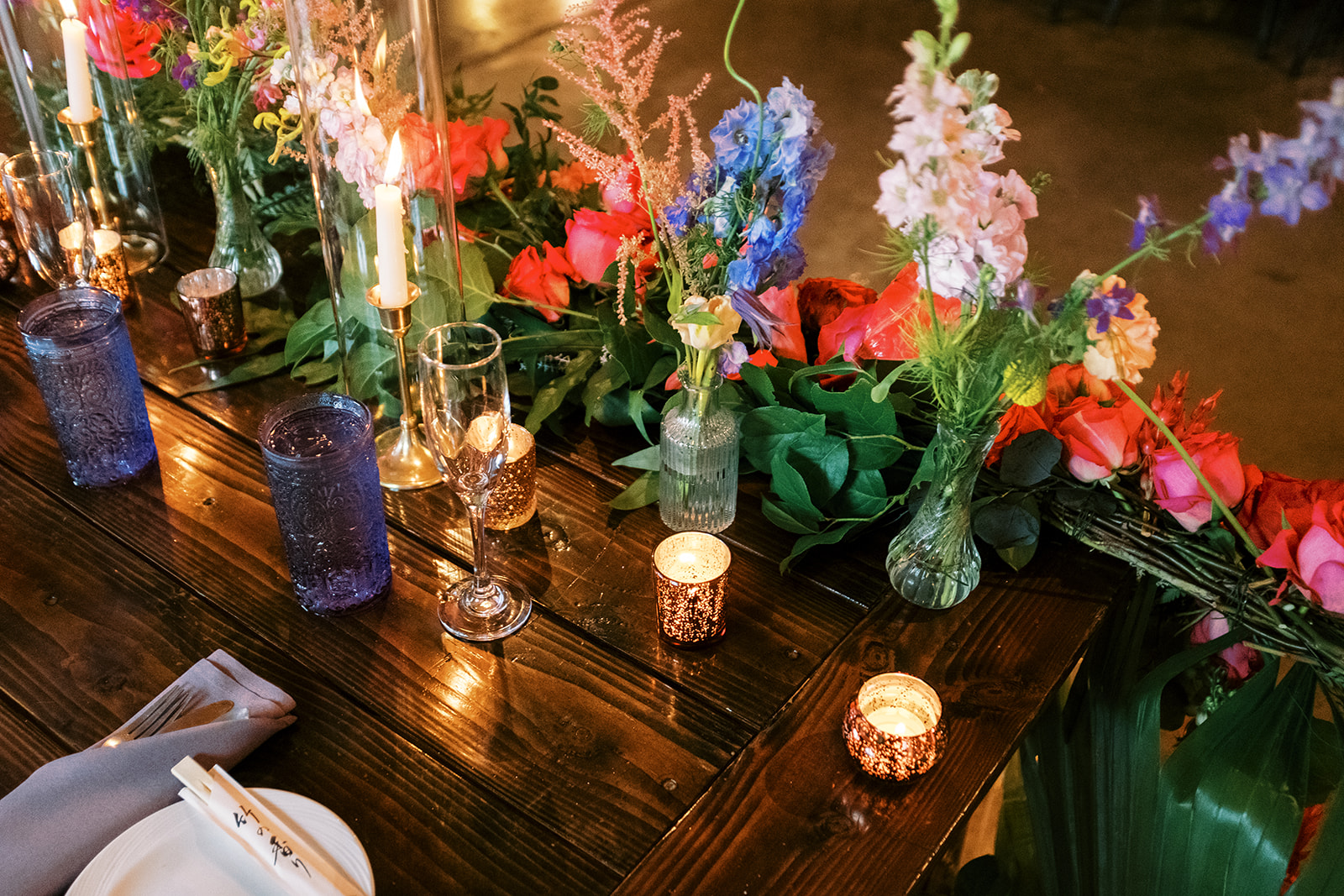 Elegant table setting with colorful floral arrangements and glowing candles for a festive event Smiths Tropical Paradise