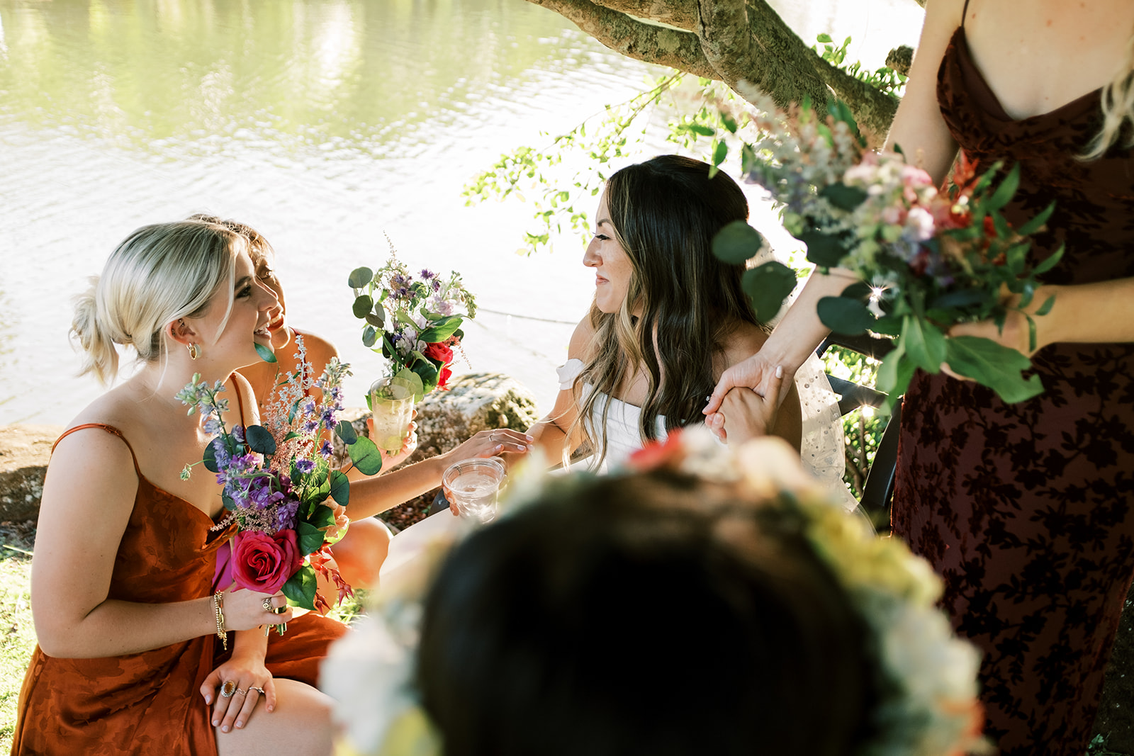Group of people in formal attire enjoying a conversation by a lakeside during a Hawaiian Wedding in Kauai