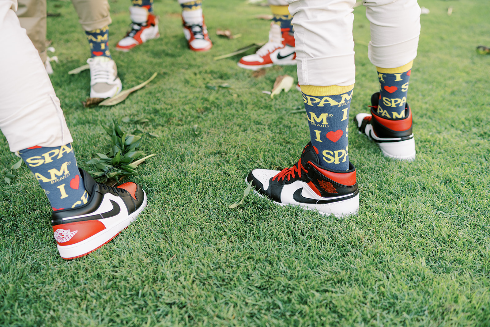 A group of people wearing sneakers and colorful socks with the word "spam" on them, standing on grass.