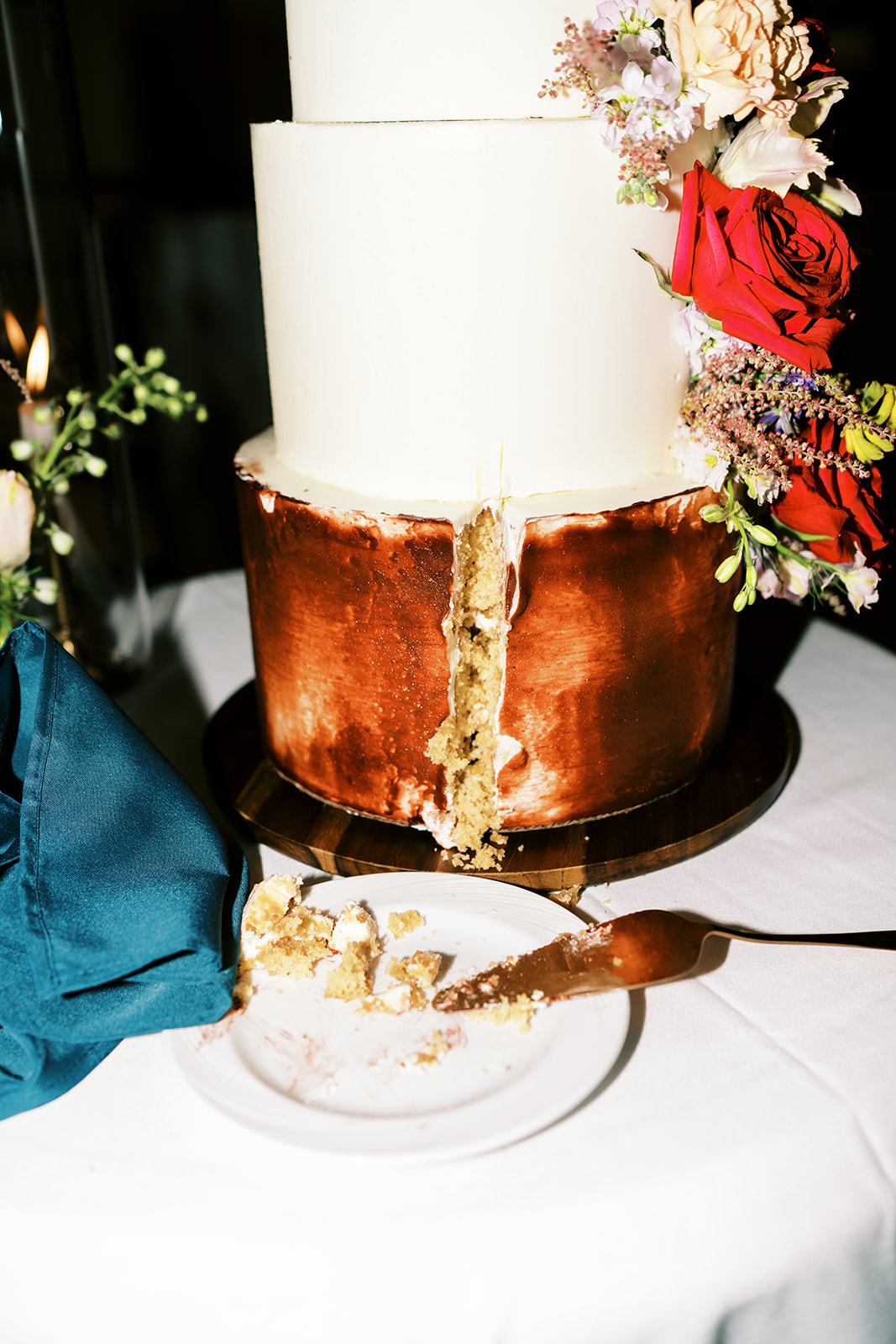 Tiered wedding cake partially sliced with one piece on a cake server captured by Megan Moura Wedding Photographer