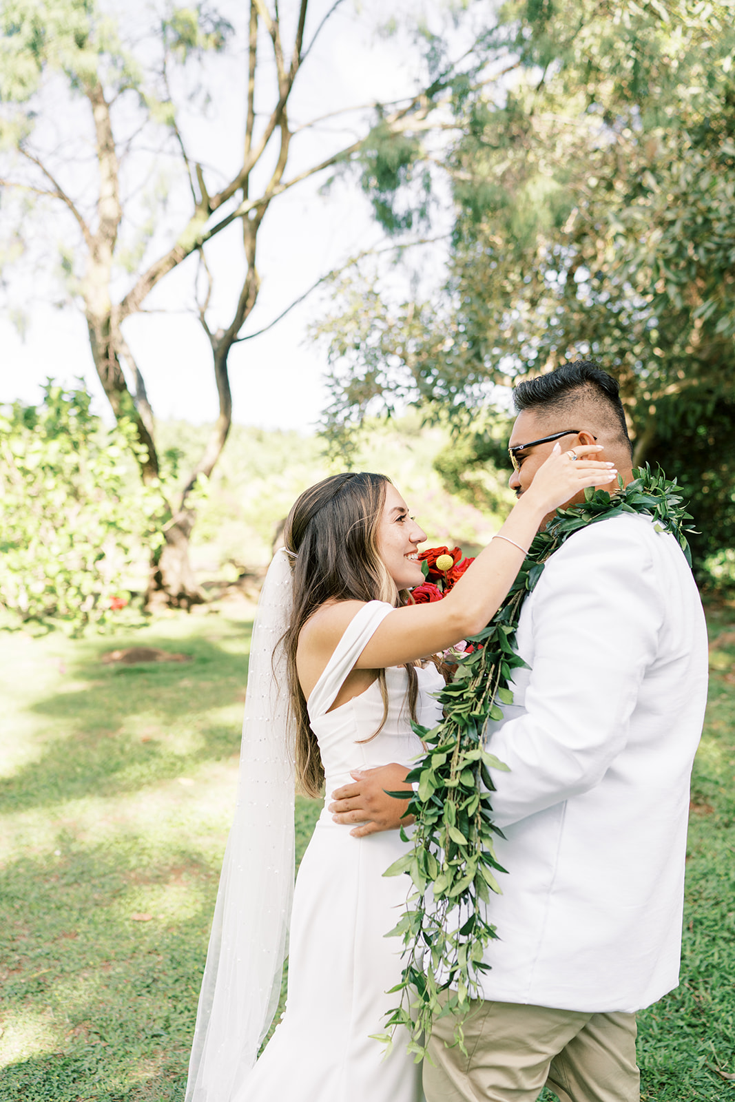 A couple in wedding attire sharing a joyful moment outdoors Smiths Tropical Paradise in Kauai