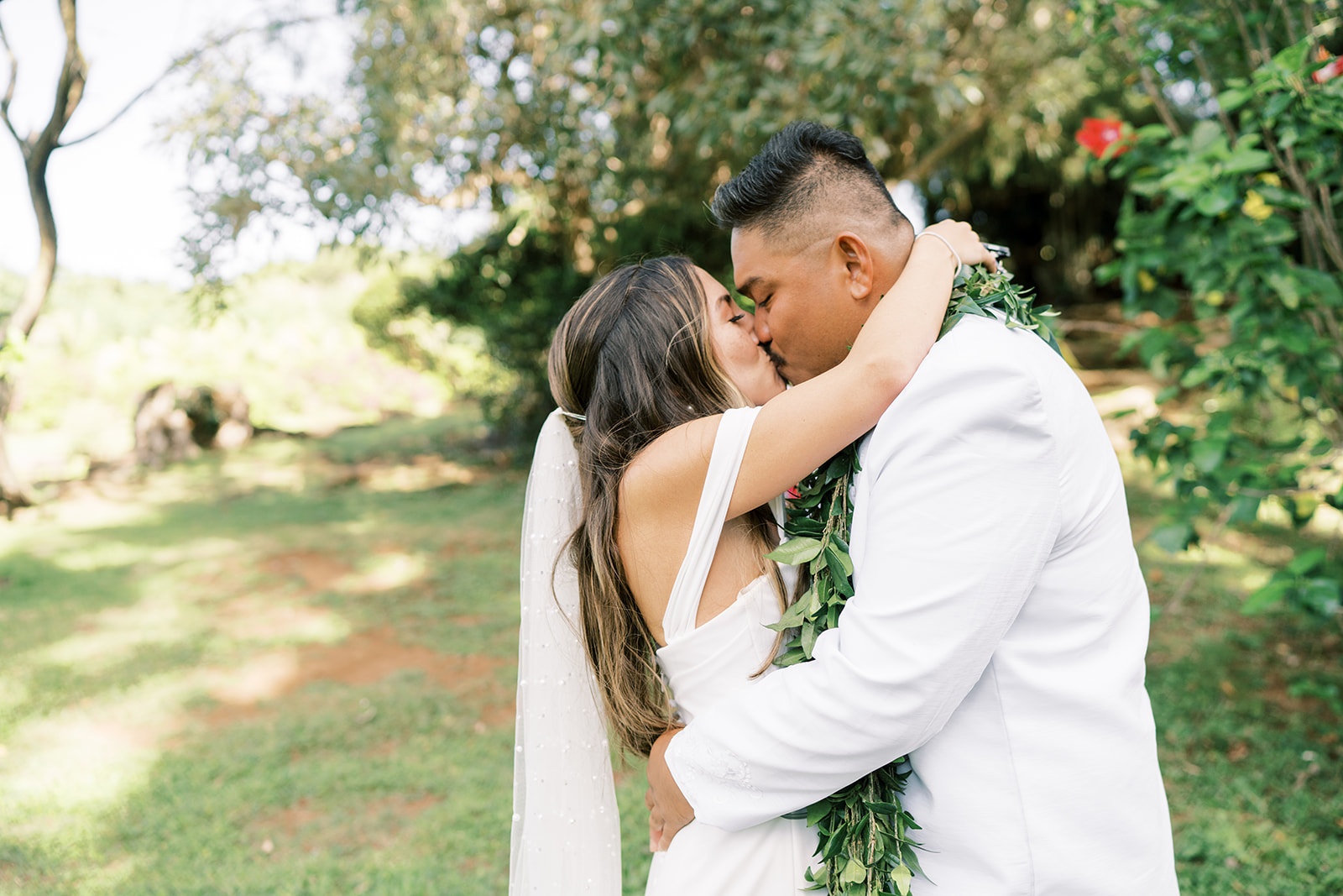 A couple embracing and kissing on their wedding day outdoors in Kauai