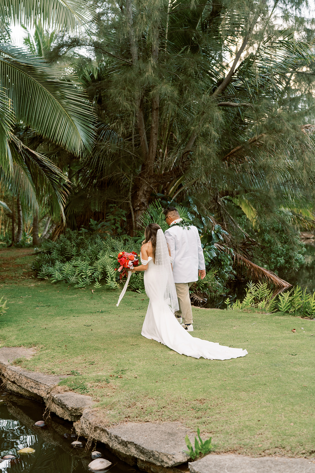 Bride and groom holding hands and walking through a lush garden in the Smiths Tropical Paradise and Luau