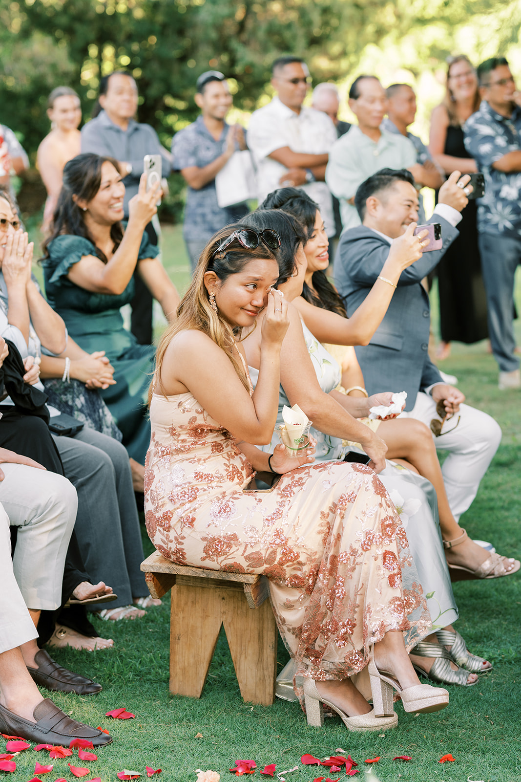 A woman seated on a small stool getting emotional during a Hawaiian Wedding Ceremony
