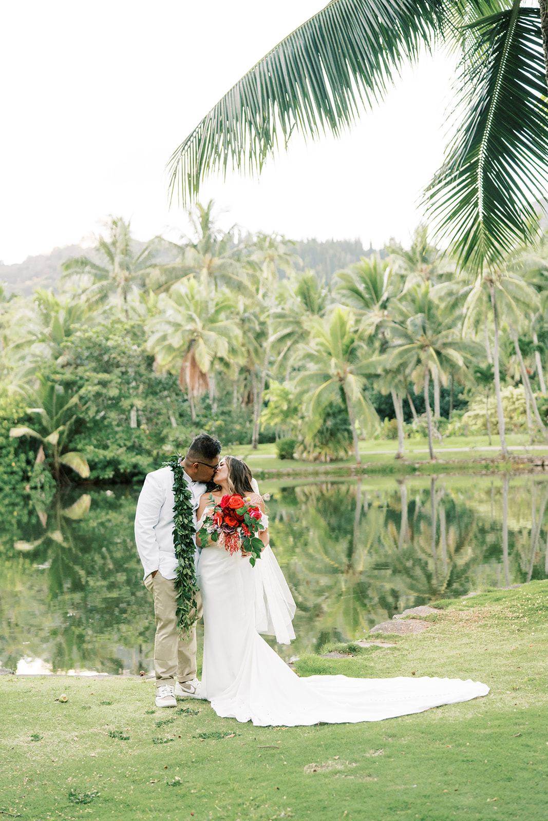 A couple in wedding attire sharing an intimate moment by a pond surrounded by lush greenery taken by Megan Moura Wedding