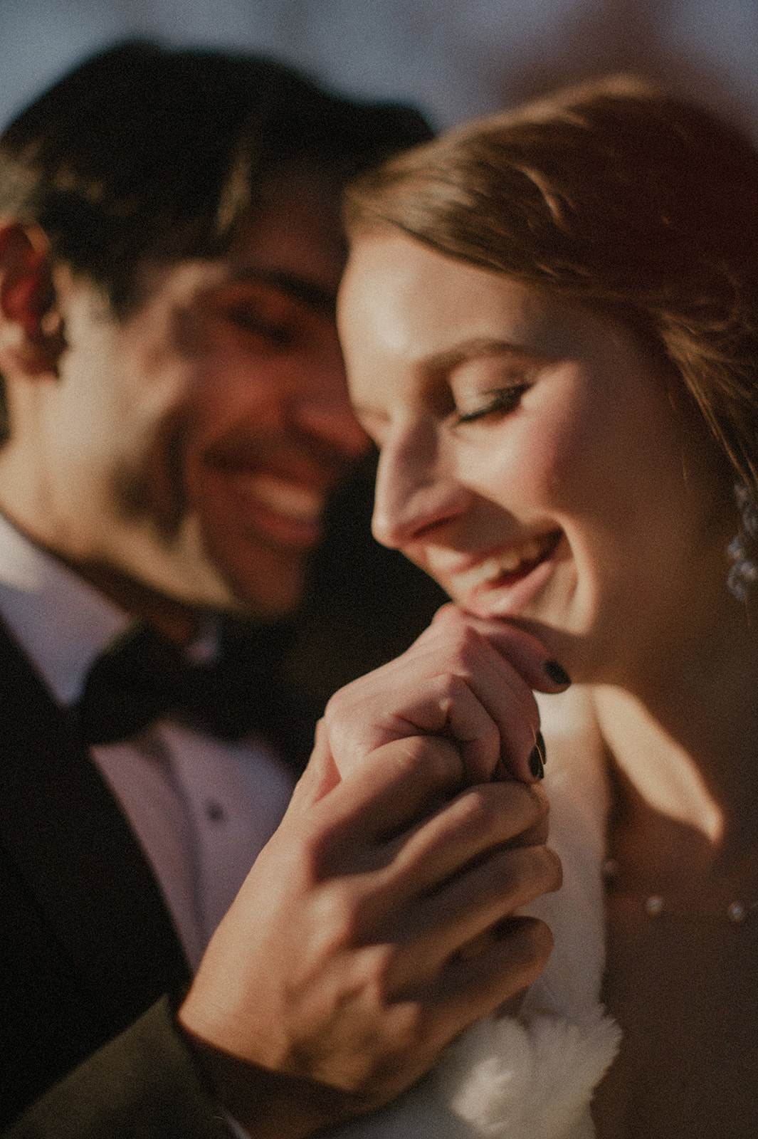 intimate closeup portrait of bride and groom laughing together in sunlight