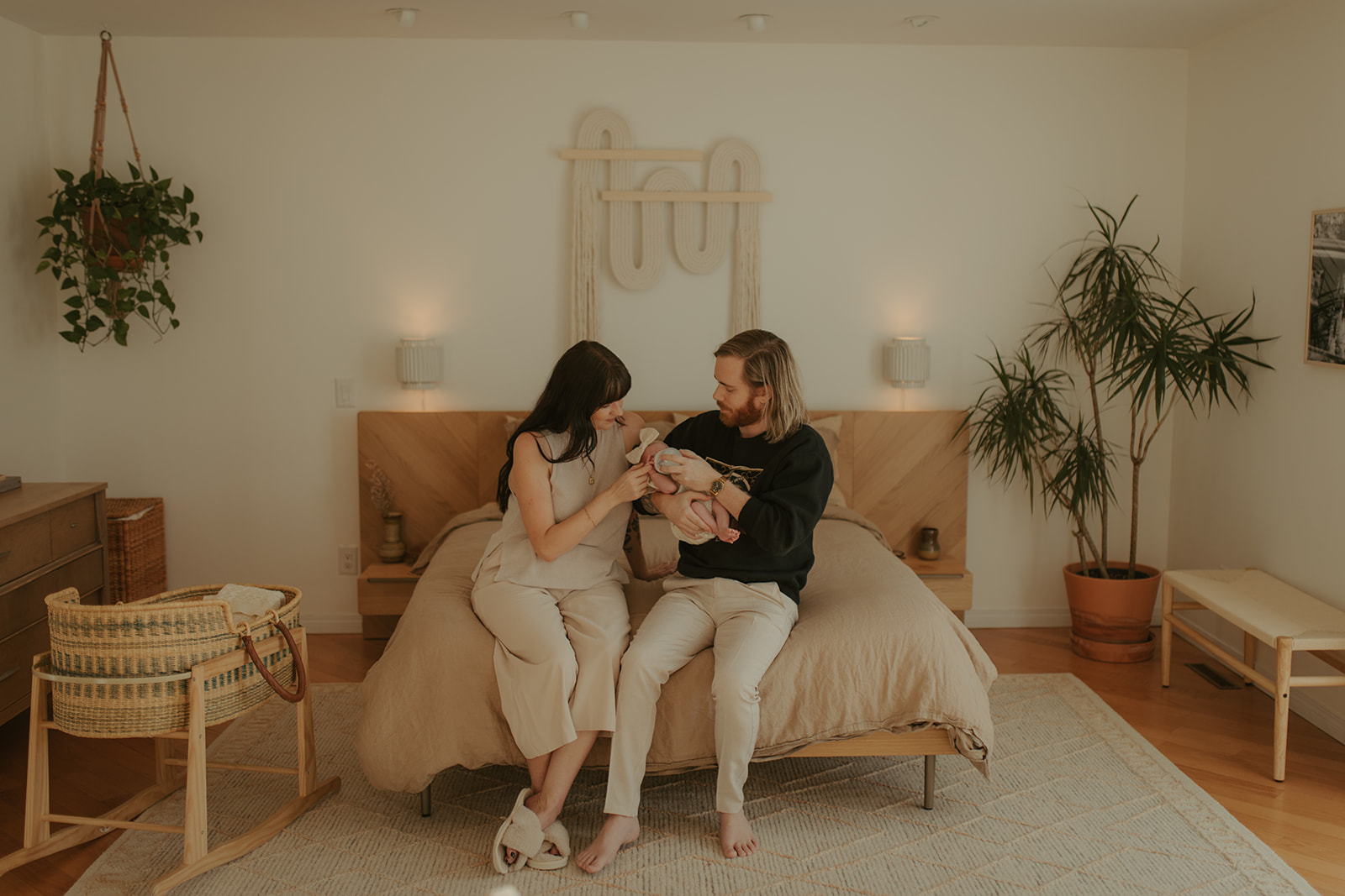mother and father holding newborn baby in their mid-century modern bedroom in Winnipeg, Manitoba