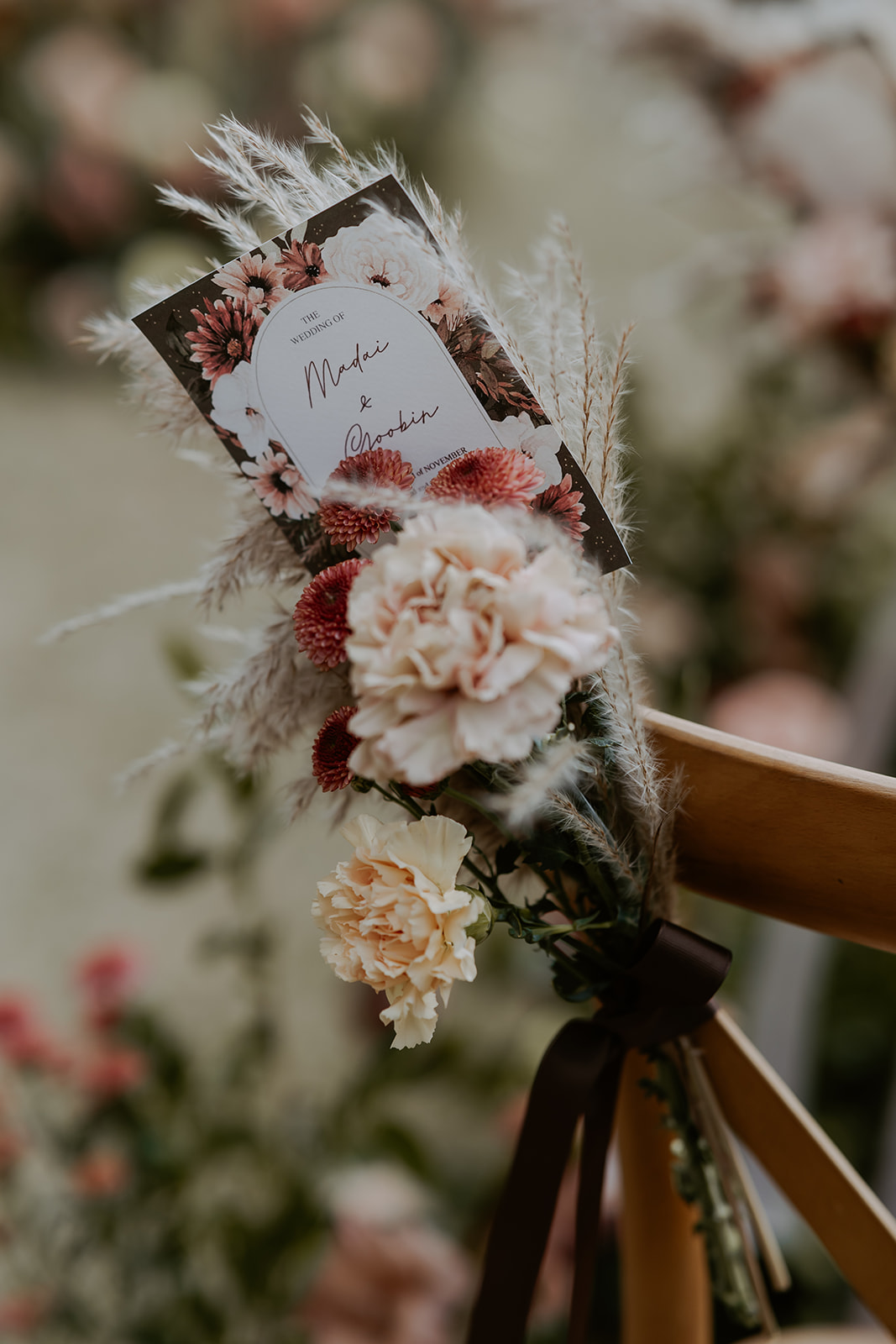 Decorated wooden chairs with floral arrangements and a name card for "mr. & mrs." at an outdoor wedding ceremony.