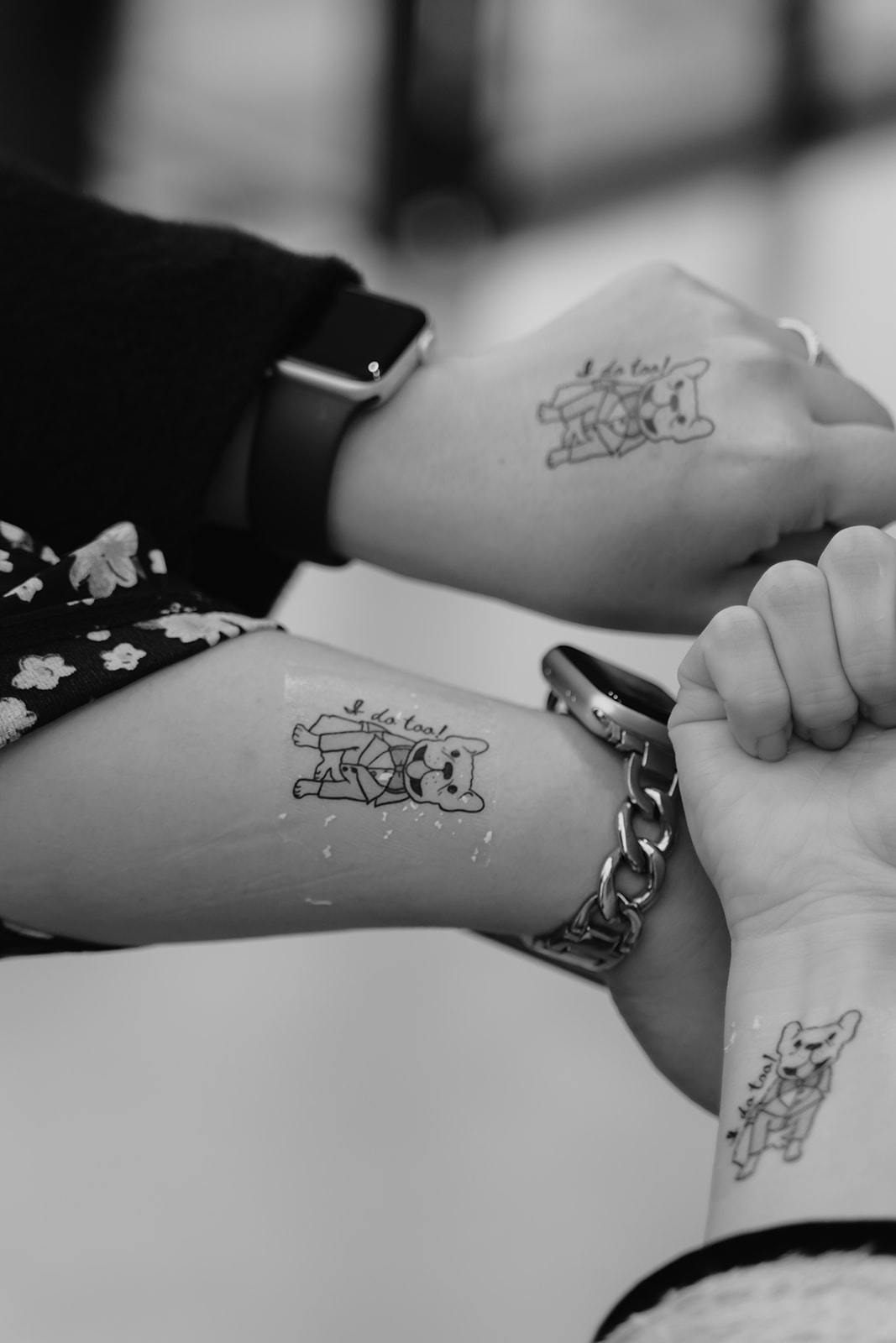 Three hands displaying temporary tattoos of whimsical drawings, with focus on the tattoos and a monochrome color scheme.