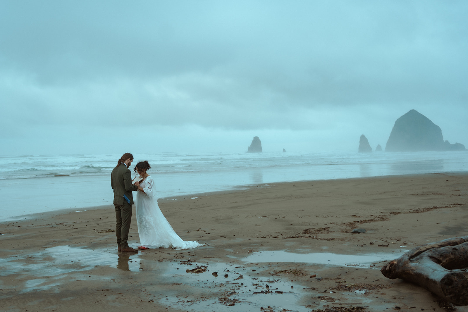 Romantic couple eloping on Cannon Beach on Oregon's moody, foggy coast. 