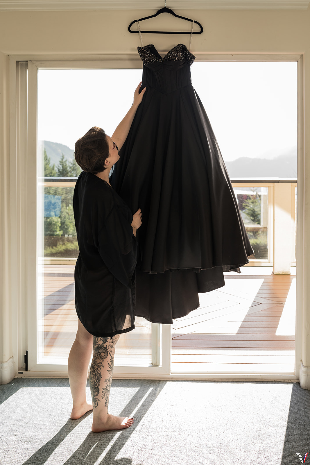 The bride was gently dressed in a black satin kimono, looking at her dress. 