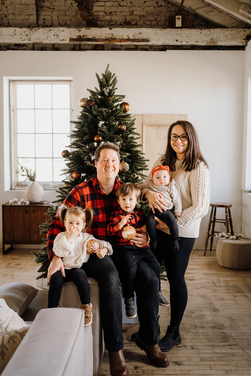 A family of five in front of a Christmas Tree.