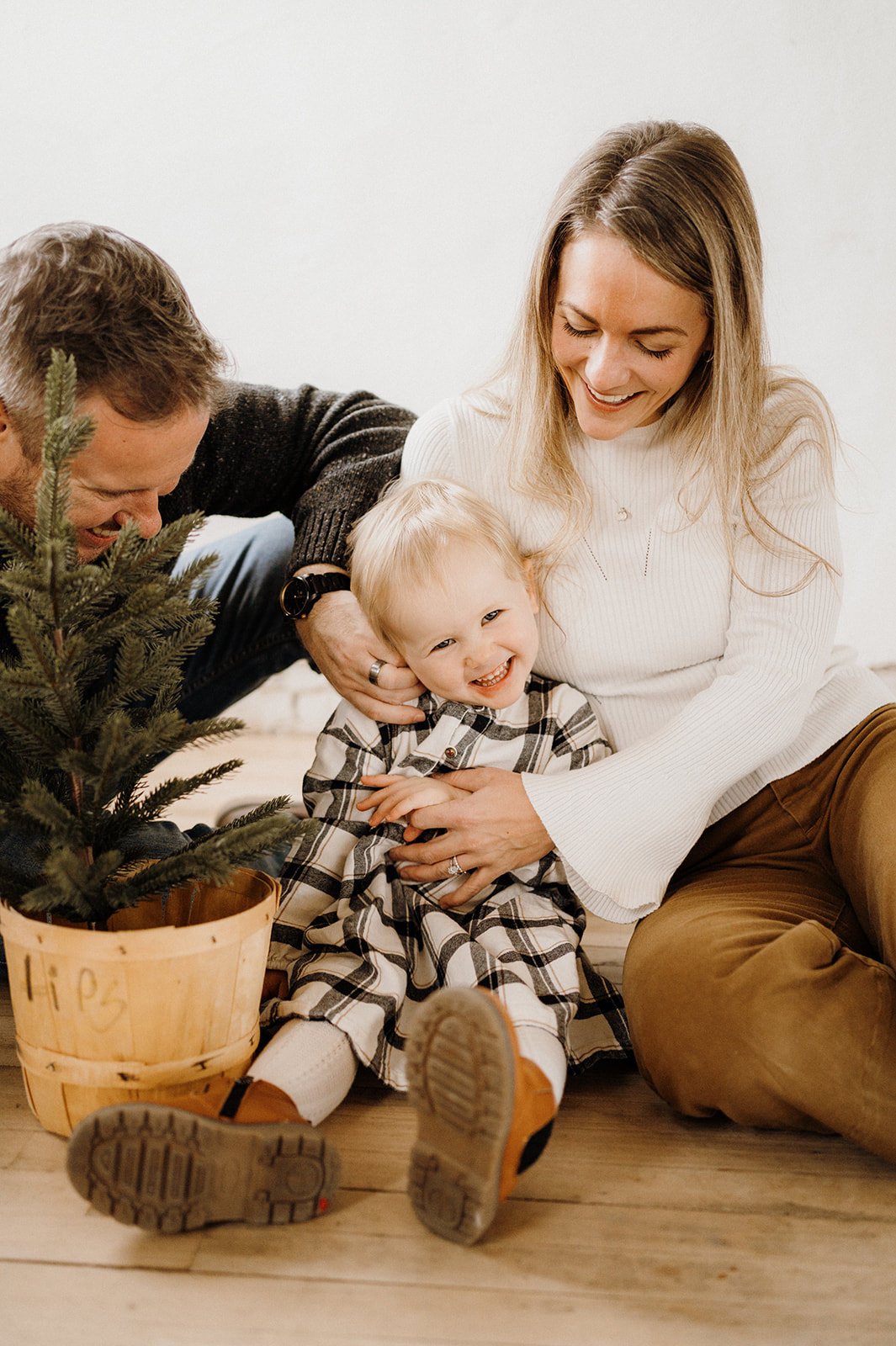 A family of three sitting around a plant inside.