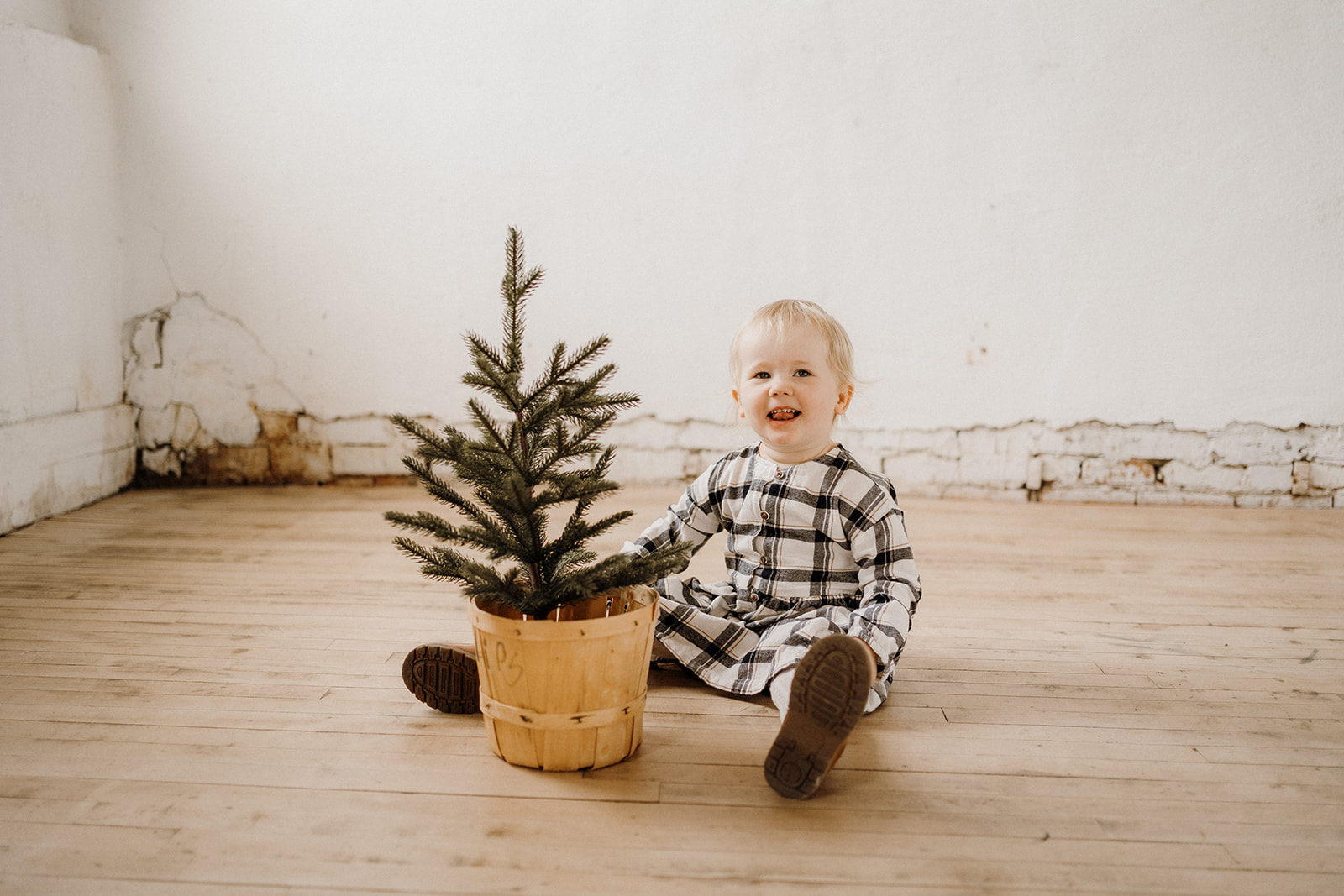 A toddler sitting with a plant inside.