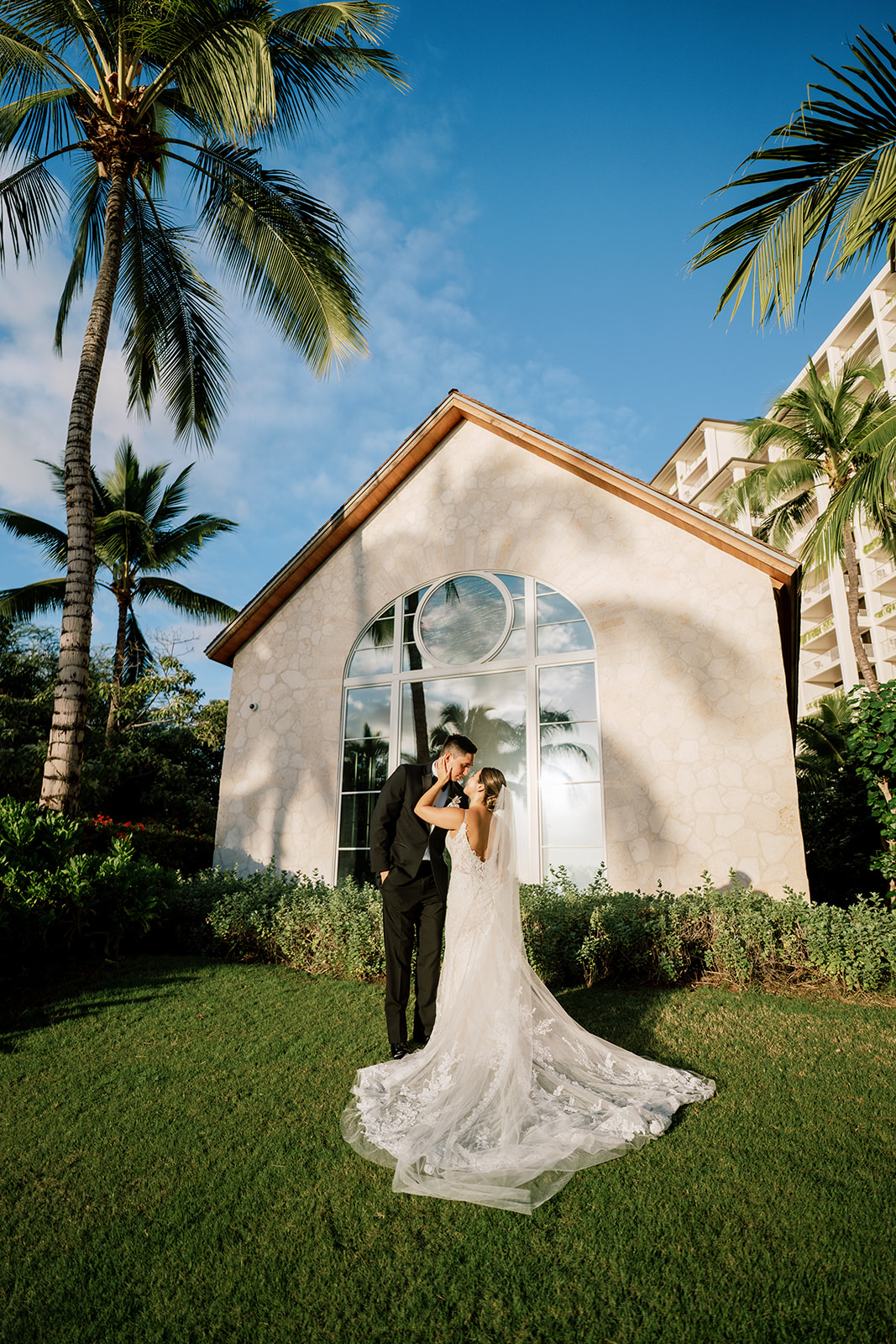 A bride and groom standing in front of the chapel of The Four Seasons Oahu