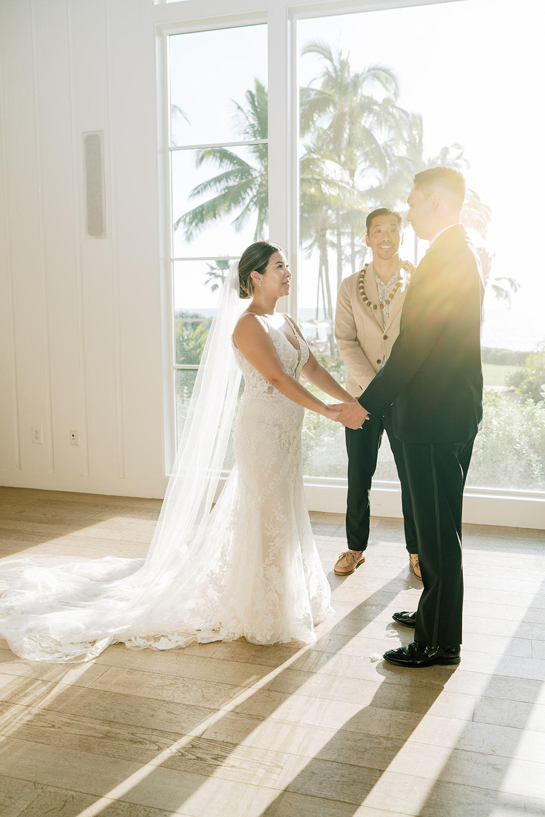 A bride and groom standing in front of a large chapel window at The Four Seasons Resort at Ko'olina Hawaii
