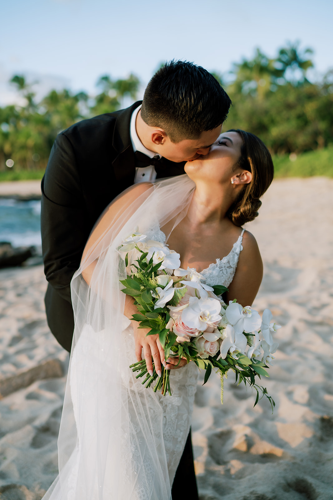 A bride and groom kissing at the Ko'olina beach The Four Seasons.