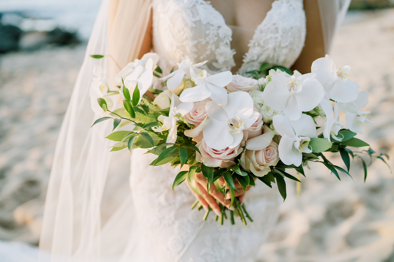 A bride holding a beautiful bouquet on the beach.