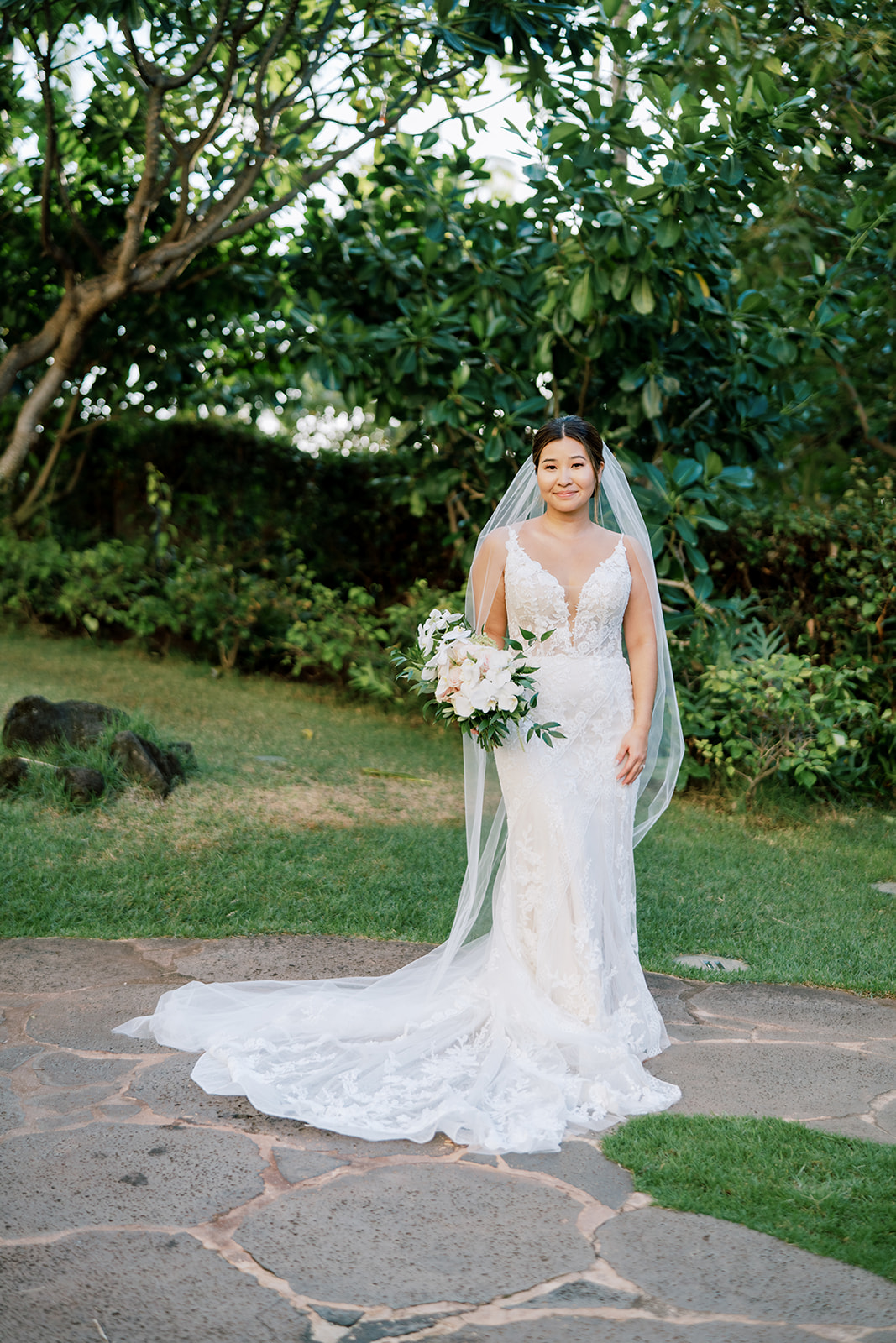 A bride in a white wedding dress standing in the garden of the Four seasons Oahu