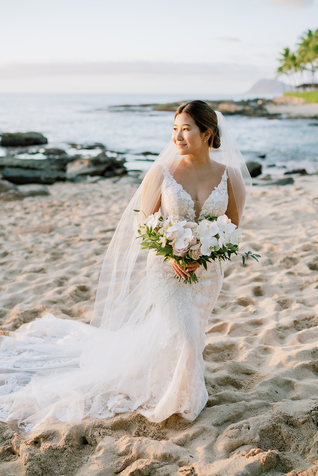 A bride standing on the beach with her wedding bouquet at Ko'olina Beach