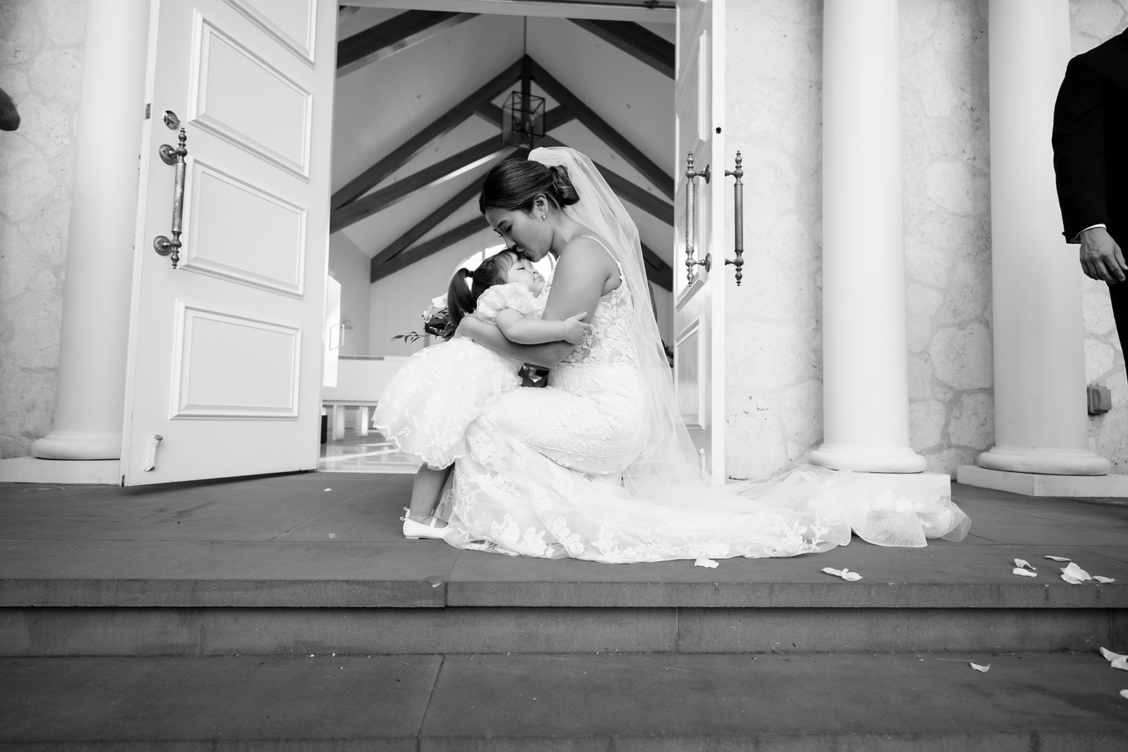 An emotional moment bride hugging her daughter sitting on the steps of a church.